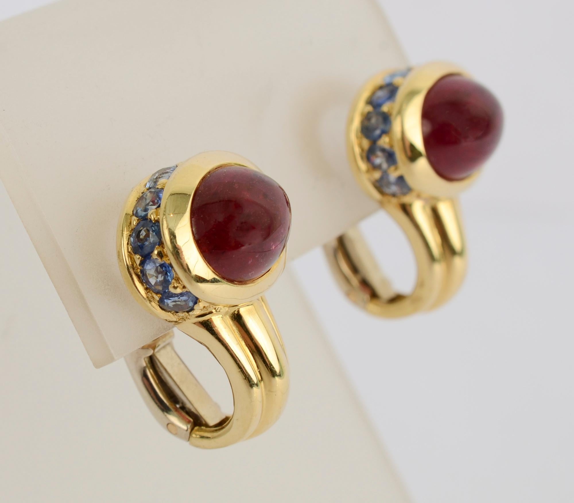 Eighteen karat gold earrings each with an oval  4 karat pink/red tourmaline surrounded by blue kunzites. The two colors combine beautifully together. Backs are posts and clips. The earrings are 7/8 