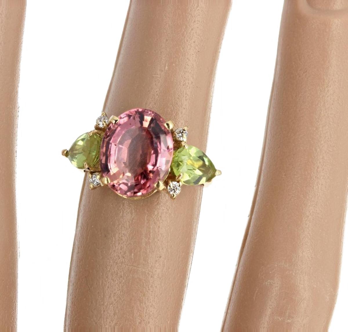 This 5 Carat brilliant Apricot Tourmaline (11.5 mm x 9.3 mm) enhanced with brilliant green pear cut Peridots and .04Ct of diamonds is set in a unique handmade 18 Kt yellow gold ring size 5 (sizable). (There are no eye visible inclusions).  This