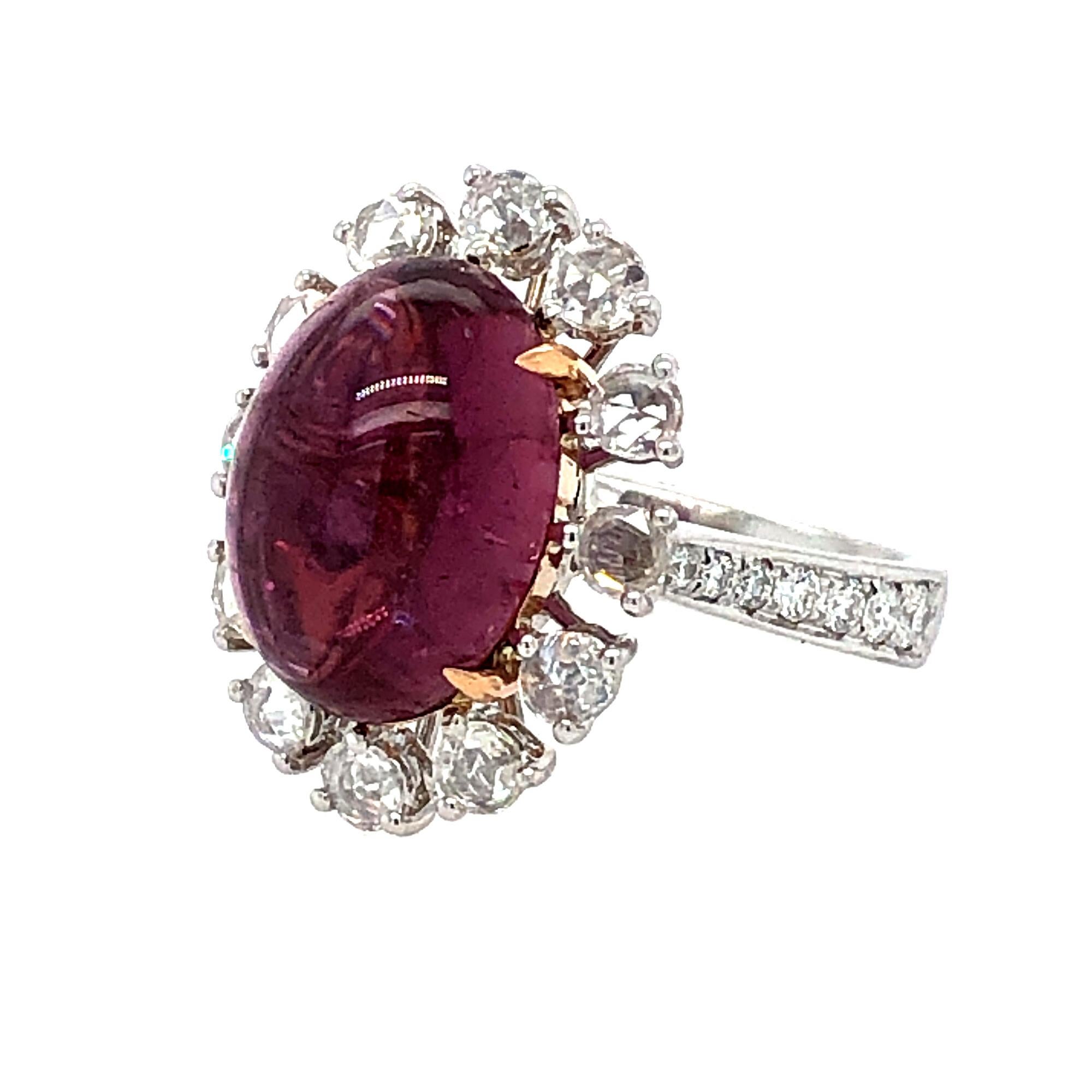 Offered here is a natural earth mined Berry color Tourmaline, cabochon cut approx. 8.00 carats. 
This pinkish red gemstone is framed with 12 large rose cut diamonds, shank is further adorned with 7 graduating modern cut diamonds on each side. 
This