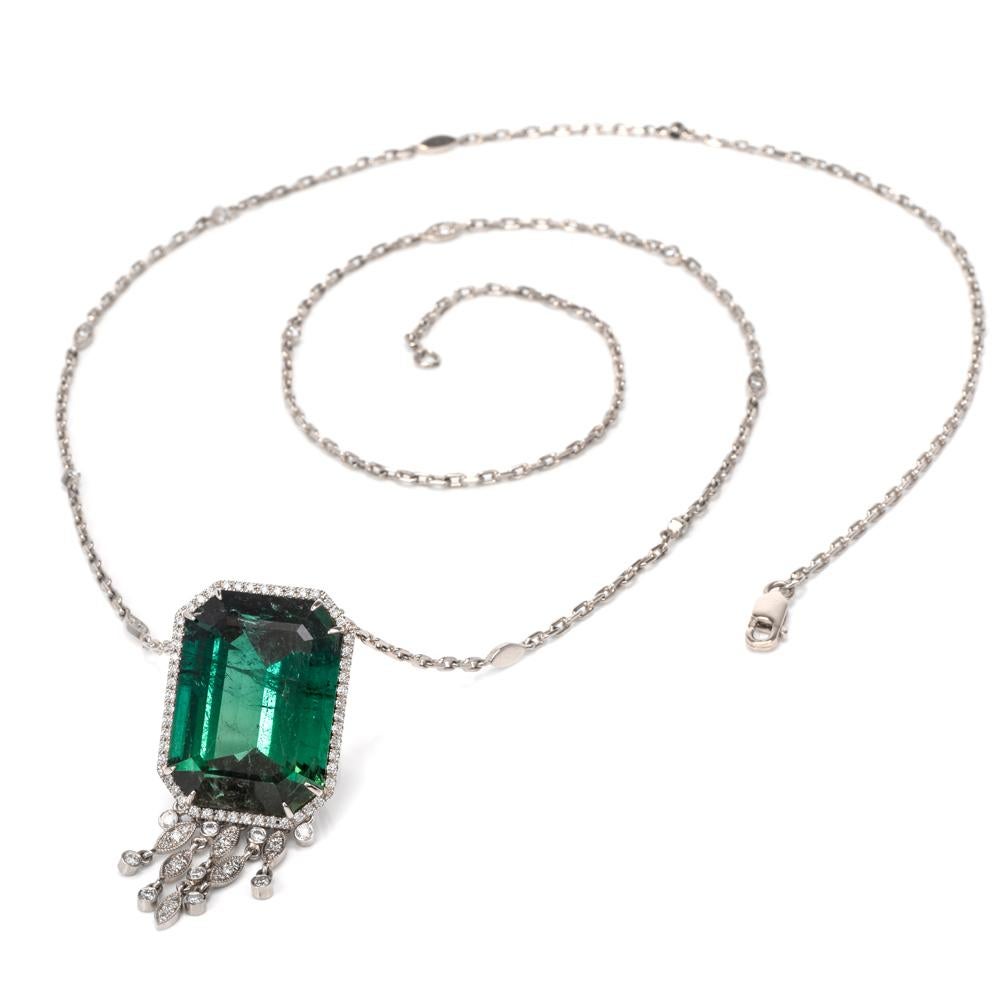This extravagant tourmaline and diamond long pendant necklace is hand crafted in 18-karat white gold. Exposing a basket set octagonal shaped forest green GIA lab report tourmaline weighing approx. 52.79 carats. Surrounded by a halo and chain