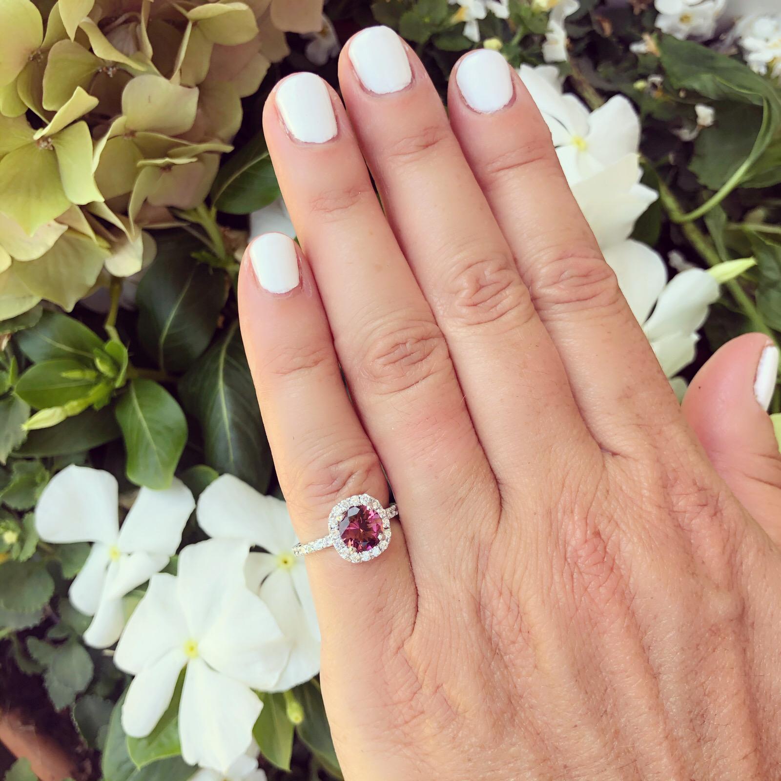 Classic halo design for simple elegance. The 14k white gold ring centers a deeply saturated round pink tourmaline weighing 1.21 carats, prong-set withing a halo of round brilliant-cut diamonds, then completed by a full eternity diamond-set band. In