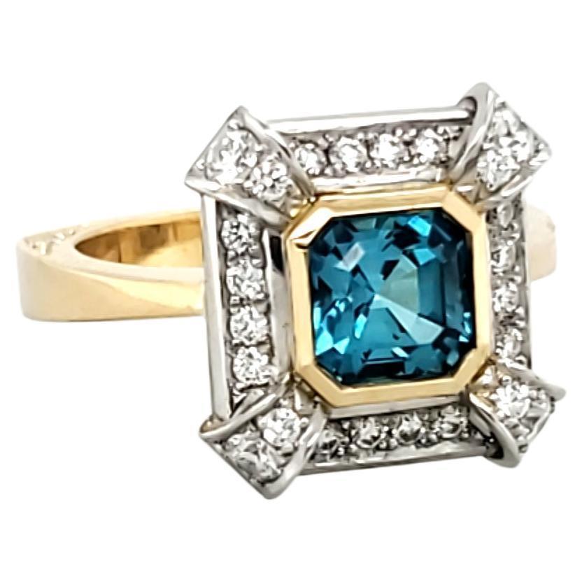 Handmade 18ct yellow gold and platinum ring. Centrally set is a gorgeous Lagoon blue Ascher cut tourmaline weighing 1.43ct. It is surrounded in a modern style Art Deco style frame of round brilliant cut diamonds with corner features. The diamonds