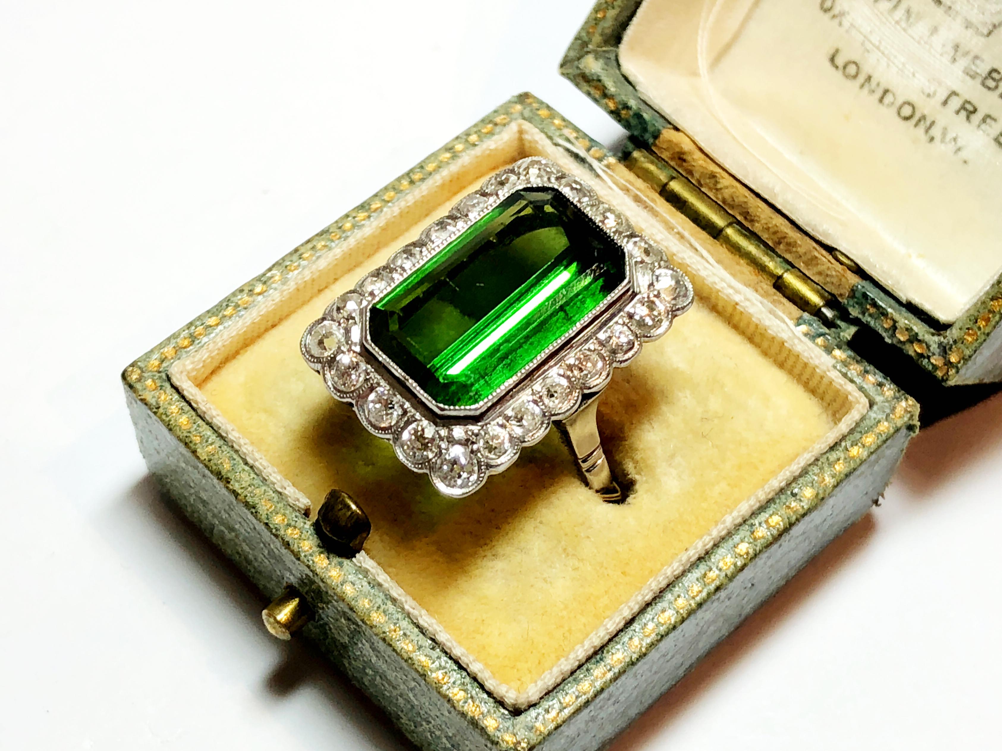 A tourmaline and diamond cluster ring, set with a step-cut dark green tourmaline, with an old-cut diamond surround, mounted in platinum.Tourmaline weighs approximately 6.00ct, the total diamond weight is approximately 1.00ct.

Finger size P½ / USA