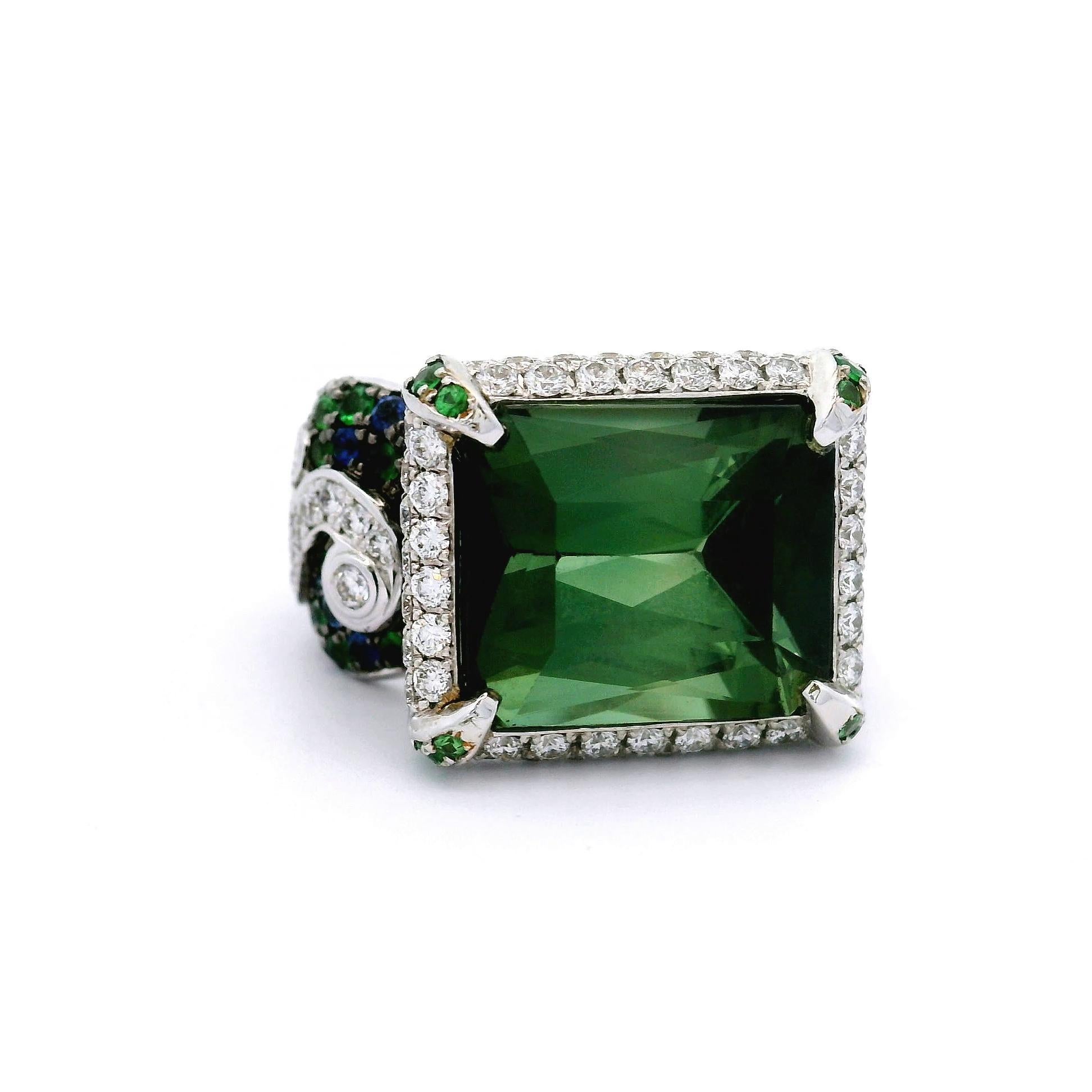 Une bague en or blanc 18k remarquable, mettant en valeur une tourmaline verte de 12,39 carats, taillée en émeraude. La pierre d'un vert éclatant est élégamment encadrée par un halo de diamants blancs ronds, totalisant 1,68 carats, qui en rehaussent