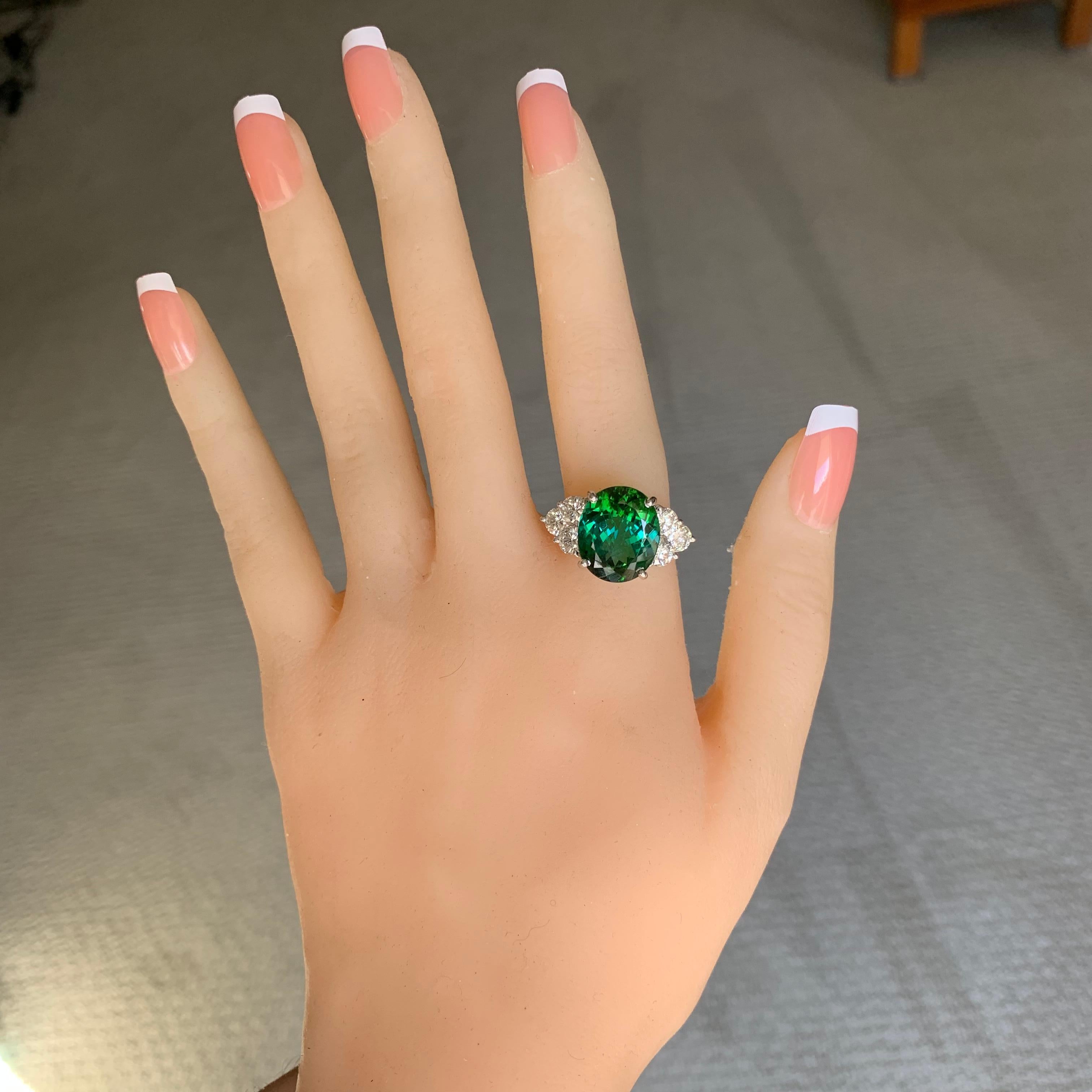 Atemberaubende 9,7 Karat TW Center ist ein ovaler grüner Turmalin in einer Hand entworfen 18k Weißgold gesetzt.

Der Stein ist mit drei runden Diamanten auf jeder Seite verziert.

Lagerbestand: B4403018

Center Stein Details: 
Edelstein-Typ: