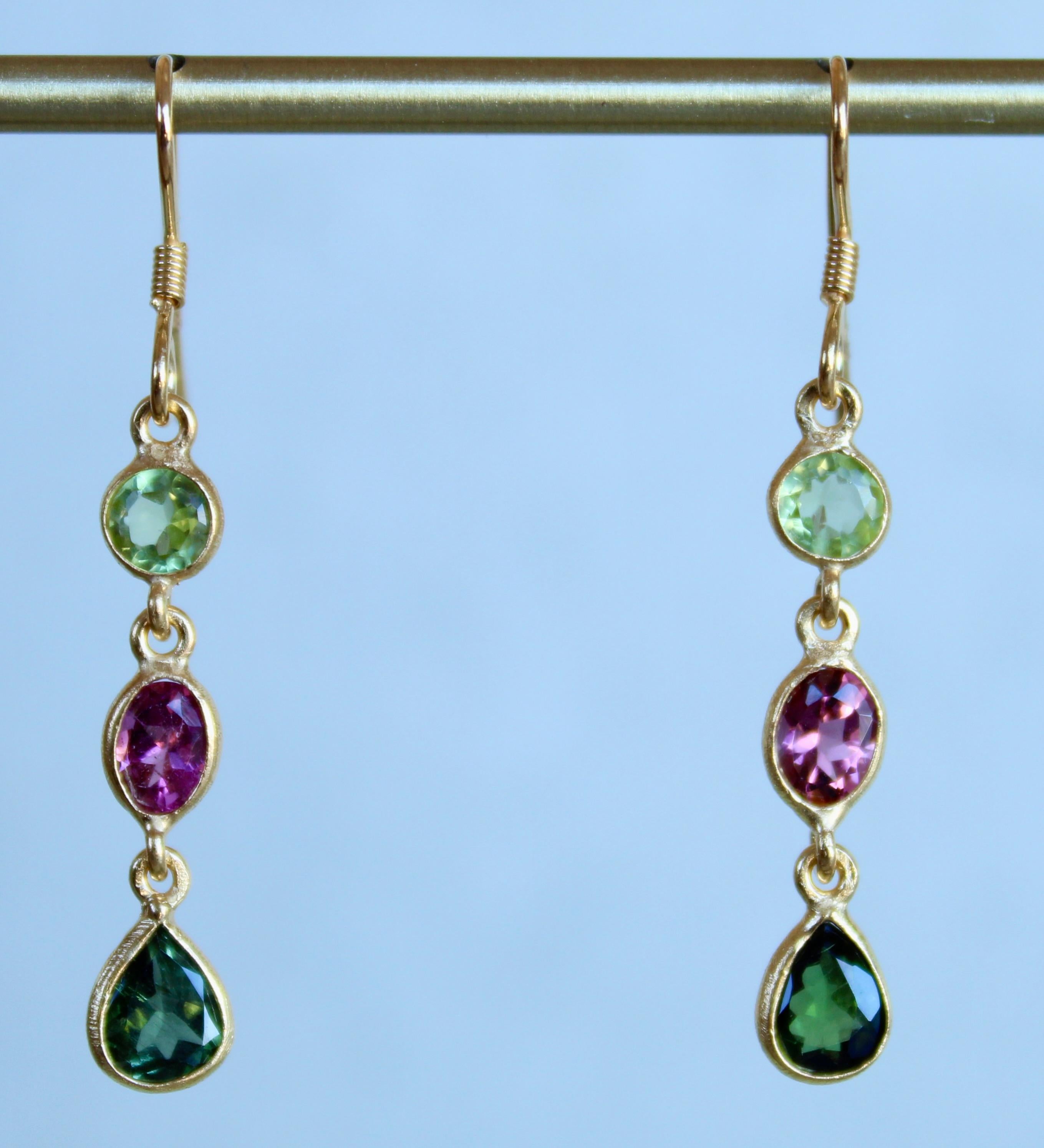 Beautiful, bright and rare these three stone dangle earrings are comprised of Peridot & Tourmaline. Each side is made up of a green Peridot round, pink Tourmaline oval and hunter green Tourmaline pear. Each stone is bezel set in 14 karat gold