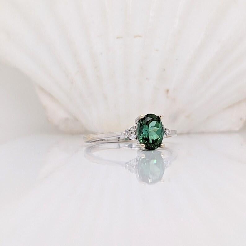 A vivid green Tourmaline looks exquisite in this elegant minimalist ring with cute round Diamond accents. A statement ring design perfect for an eye catching engagement or anniversary. This ring also makes a beautiful October birthstone ring for