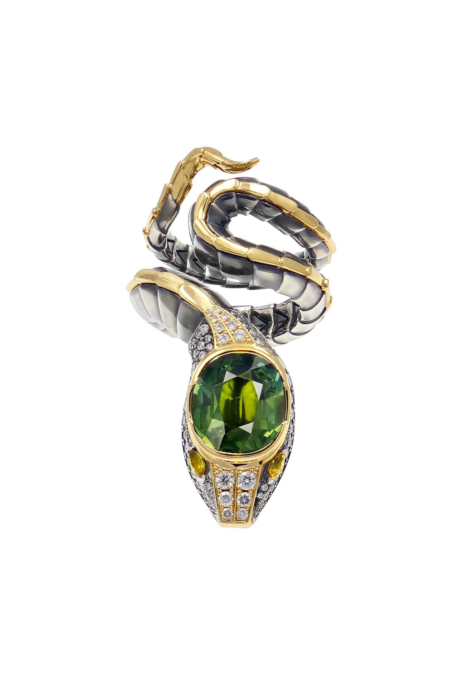 Yellow gold and distressed silver ring. The body, wrapped in distressed silver scales with a yellow gold dorsal ridge, ends with a head that is paved with diamonds and animated with  yellow sapphire eyes. At its summit, it is set with a green 