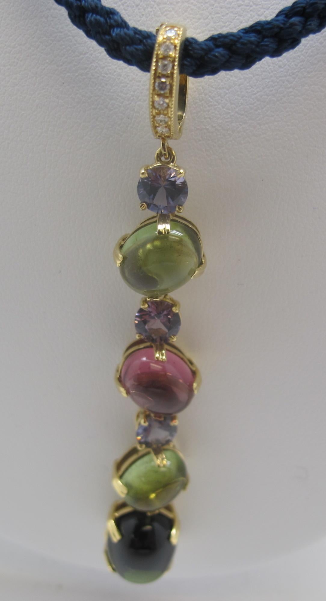 This pretty handmade enhancer features multi-colored tourmaline cabochons set in a dramatic dangle with round, faceted spinels. The pink and green shades of the tourmalines are accented beautifully by the lavender and violet shades of the faceted