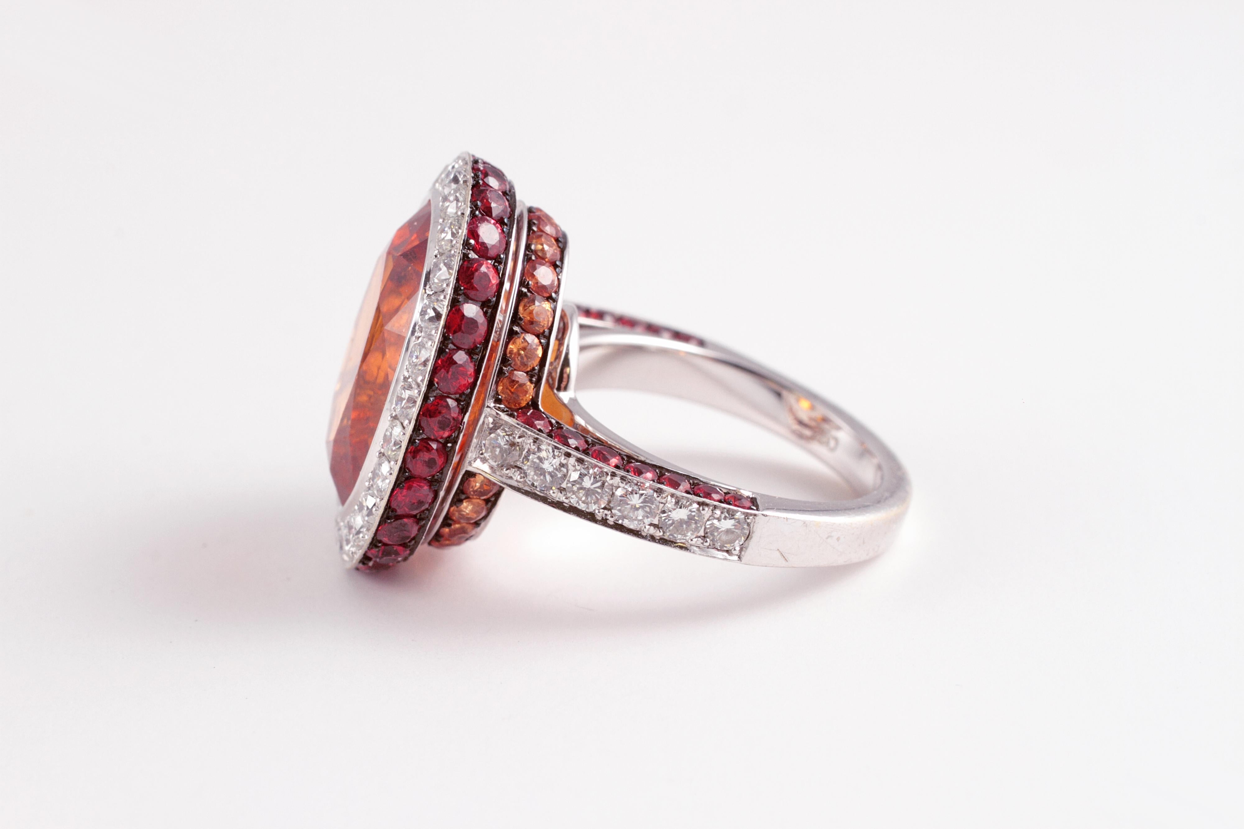 Exquisite Mandarin garnet and diamond ring!  The 15.32 oval-shaped Mandarin garnet is bezel set and surrounded by 1.45 carats of diamonds, SI in clarity and G - H in color, along with 2.06 carats of red sapphires and 0.79 carats of orange sapphires,