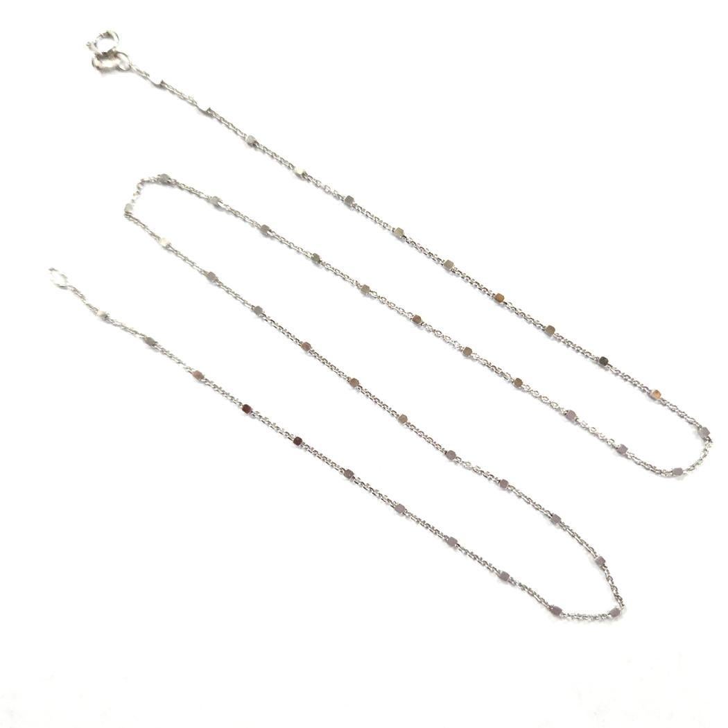 Questa elegante collana di Tous è realizzata in oro bianco 18 carati, prodotta in Spagna e disegnata con la tipica estetica minimal del marchio. La sottile catena misura 16 pollici di lunghezza e presenta delicate interruzioni a forma di cubo che si