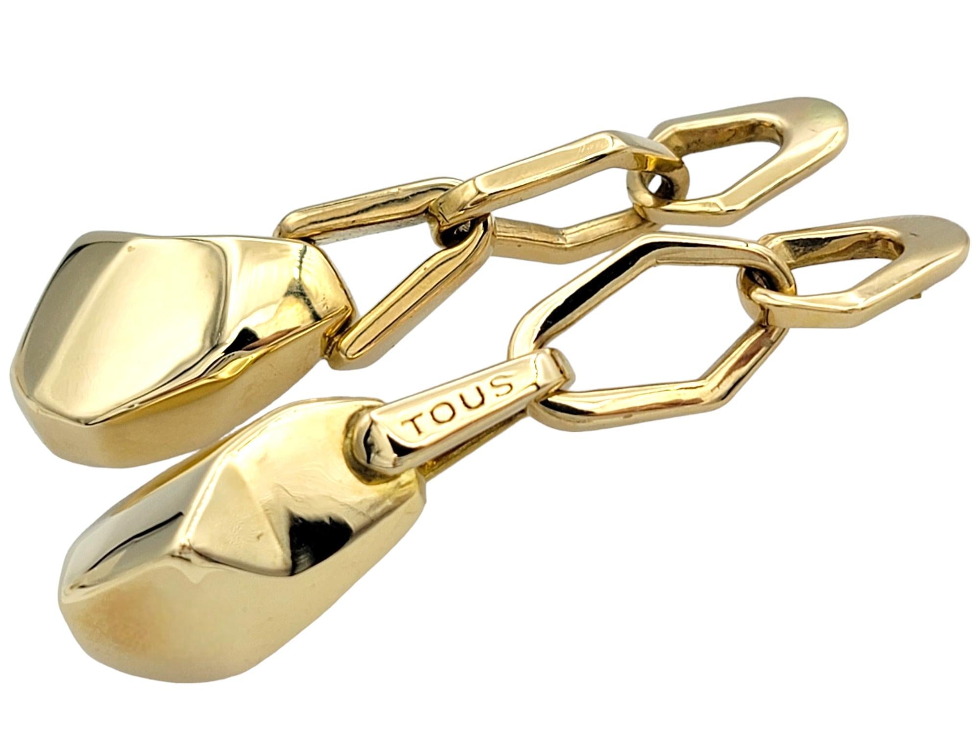Scopri l'eleganza di Tous con questi splendidi orecchini pendenti in giallo 18 carati. Questi splendidi orecchini allungati sono caratterizzati da un moderno design geometrico che combina linee eleganti e forme audaci per creare un effetto visivo