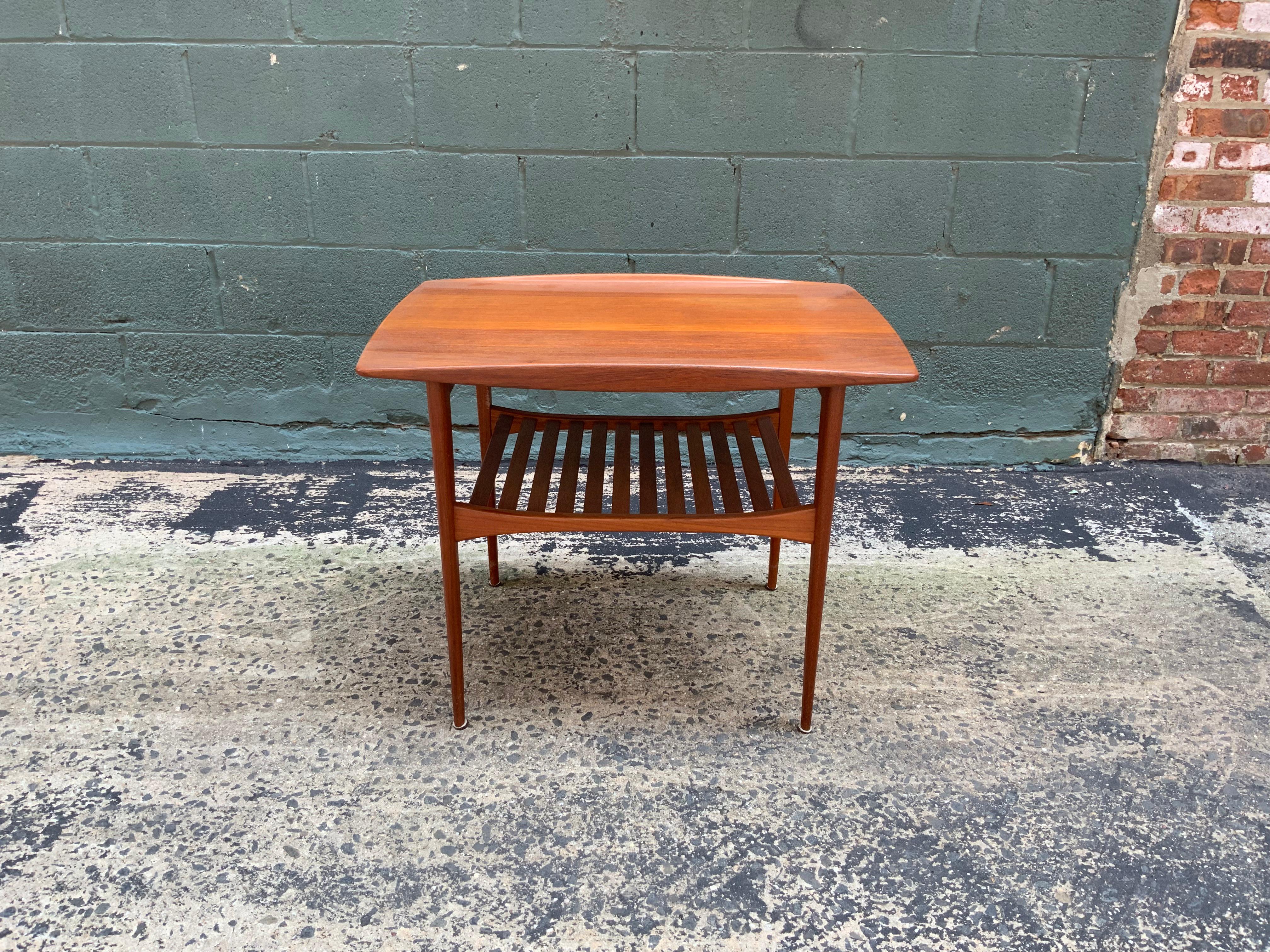 Solid teak elegant Danish side table design by Tove and Edvard Kindt-Larsen for France and Daverkosen, circa 1960. Gorgeous tapered legs and slatted lower shelf. Amazing profile lines. John Stuart enamel button and France and Daverkosen stamp on the