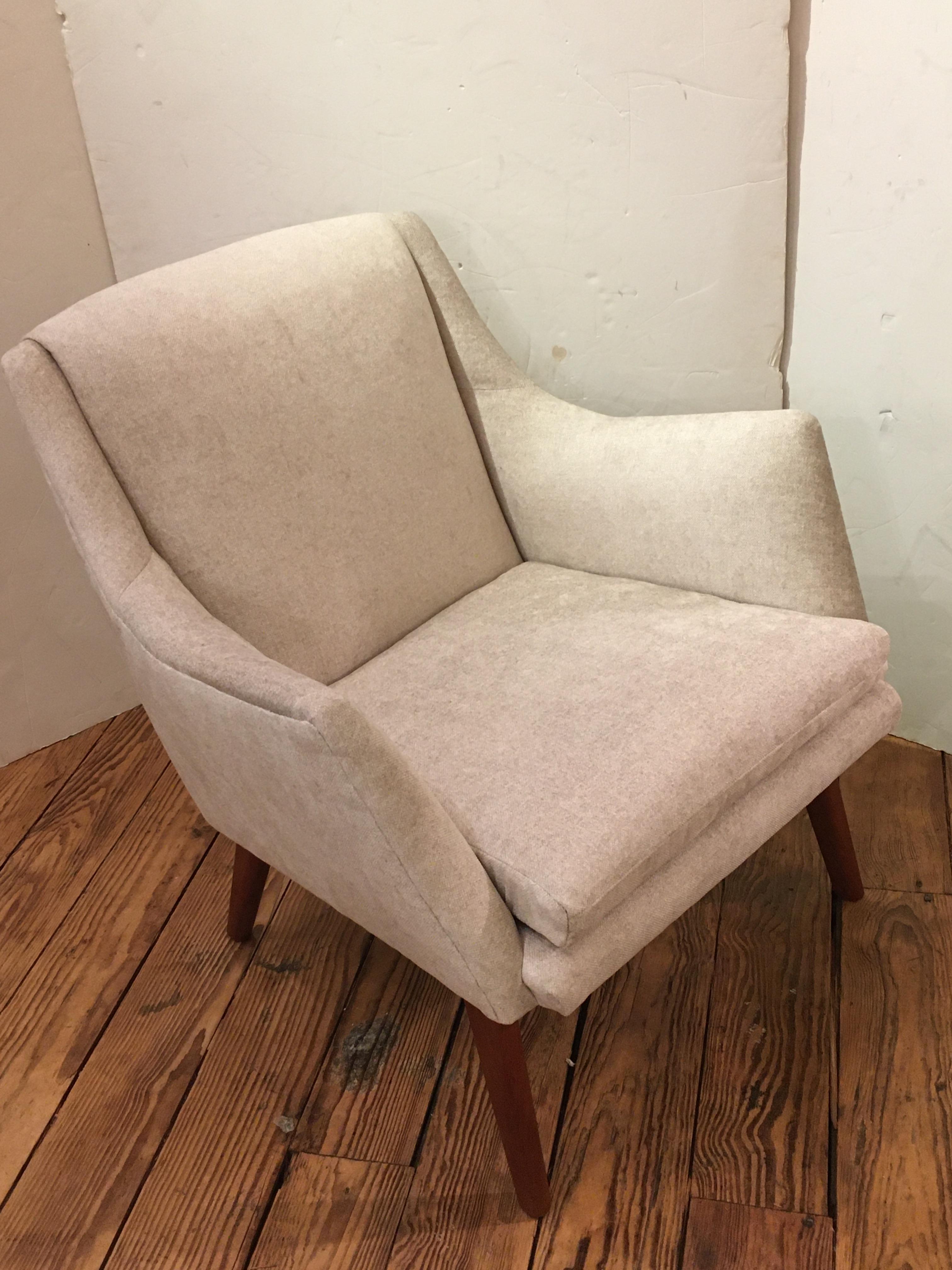 A stylish Danish modern 1950s club chair having streamline silhouette and teak legs. Brand new style appropriate cream upholstery is neutral and chic.