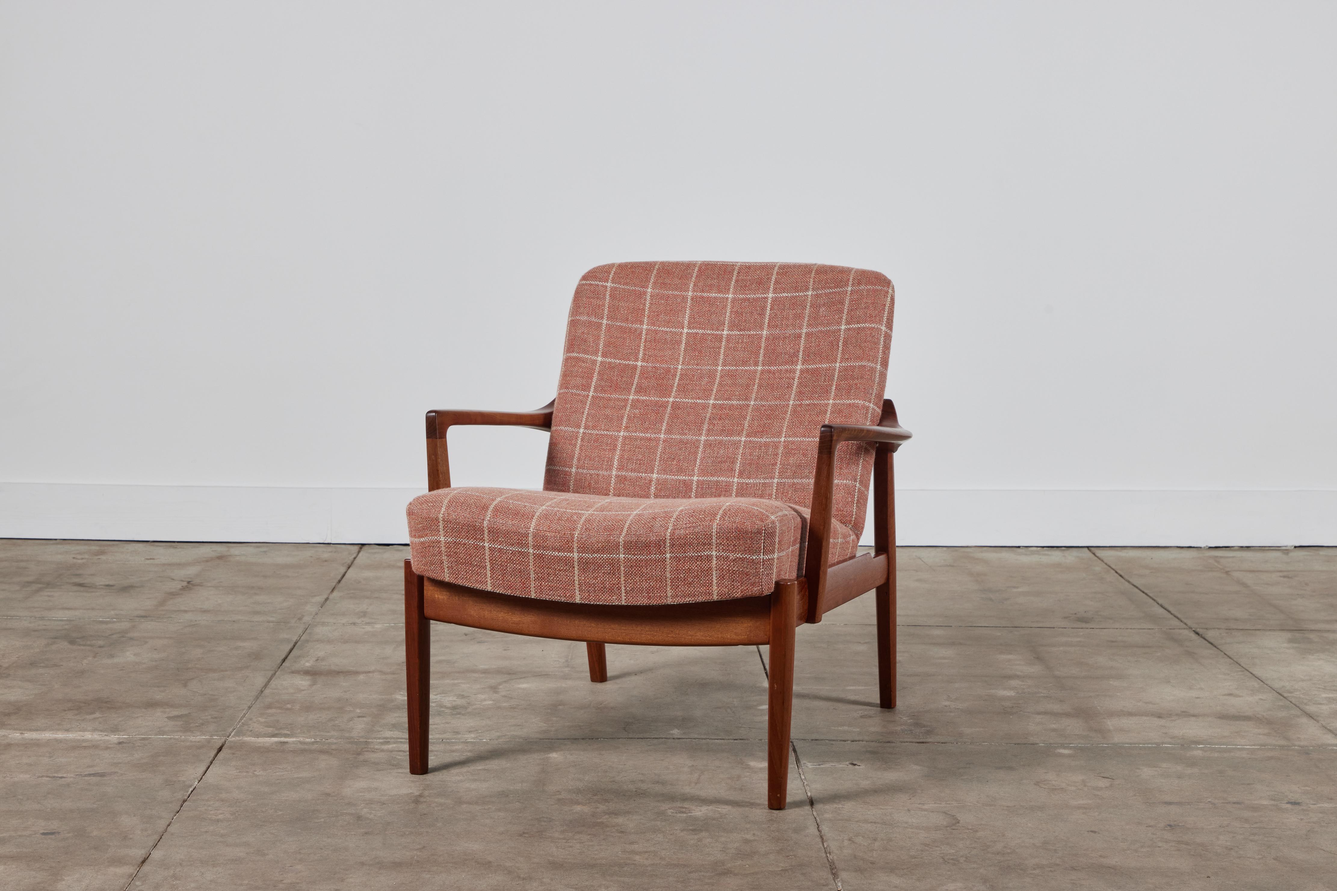 A low, Danish lounge chair by husband-and-wife design team Tove and Edvard Kindt-Larsen for France & Son. This example from 1958 has a teak frame around fixed cushions, upholstered in a window pane wool blend fabric. The design is distinguished by