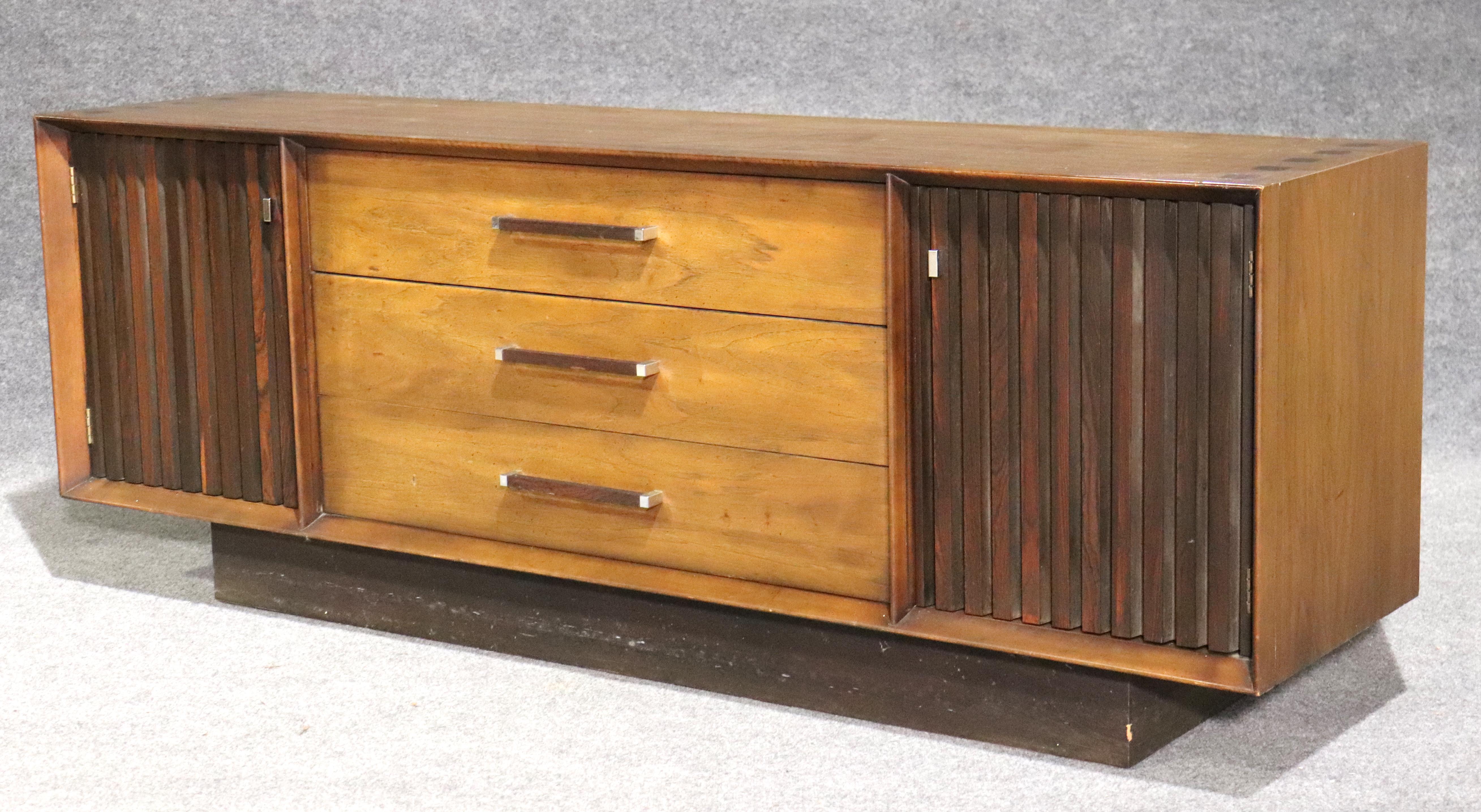 Beautiful mix of woods set in this long sideboard with cabinet storage and drawers. Designed by Lane Furniture for their Tower Suite collection, featuring walnut wood with contrasting rosewood front and inlay top.
Please confirm location.