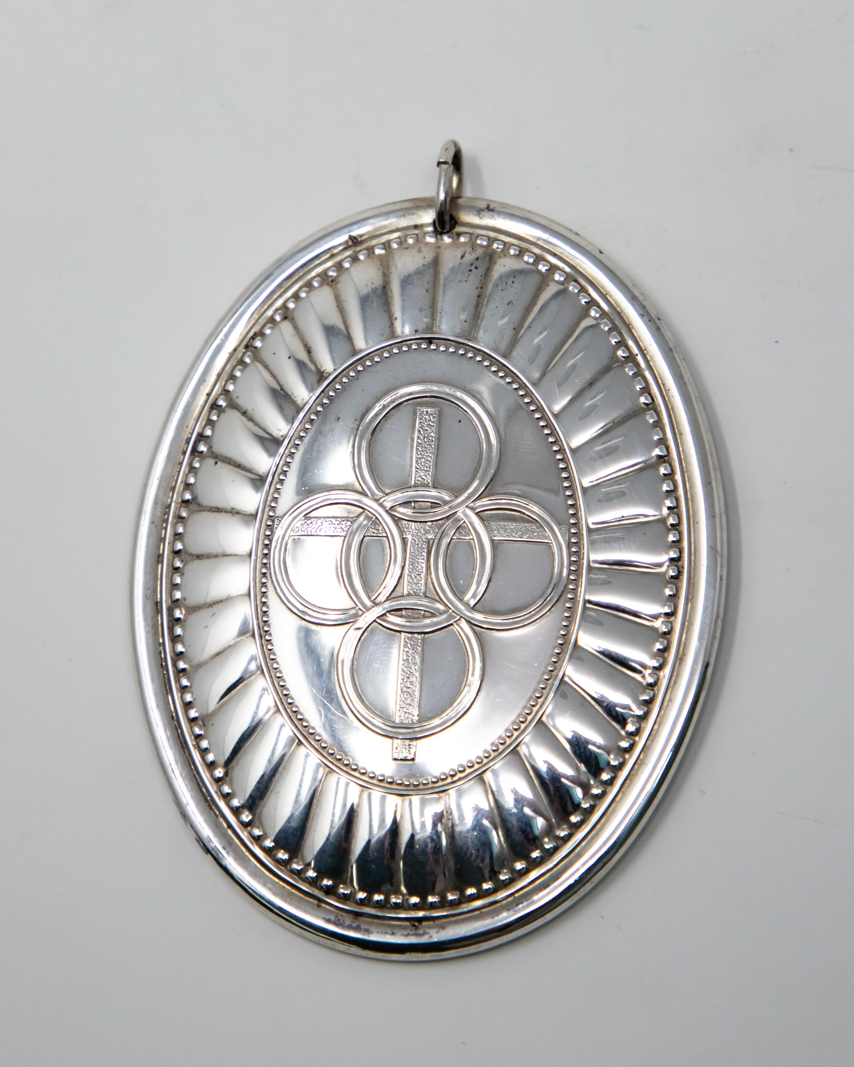 Offering this stunning Towle sterling silver ornament from 1975. This is part of the twelve days of Christmas and is five golden rings. In behind that is a cross and has simple geometric lines and dots around that. The back has beautiful scrollwork,
