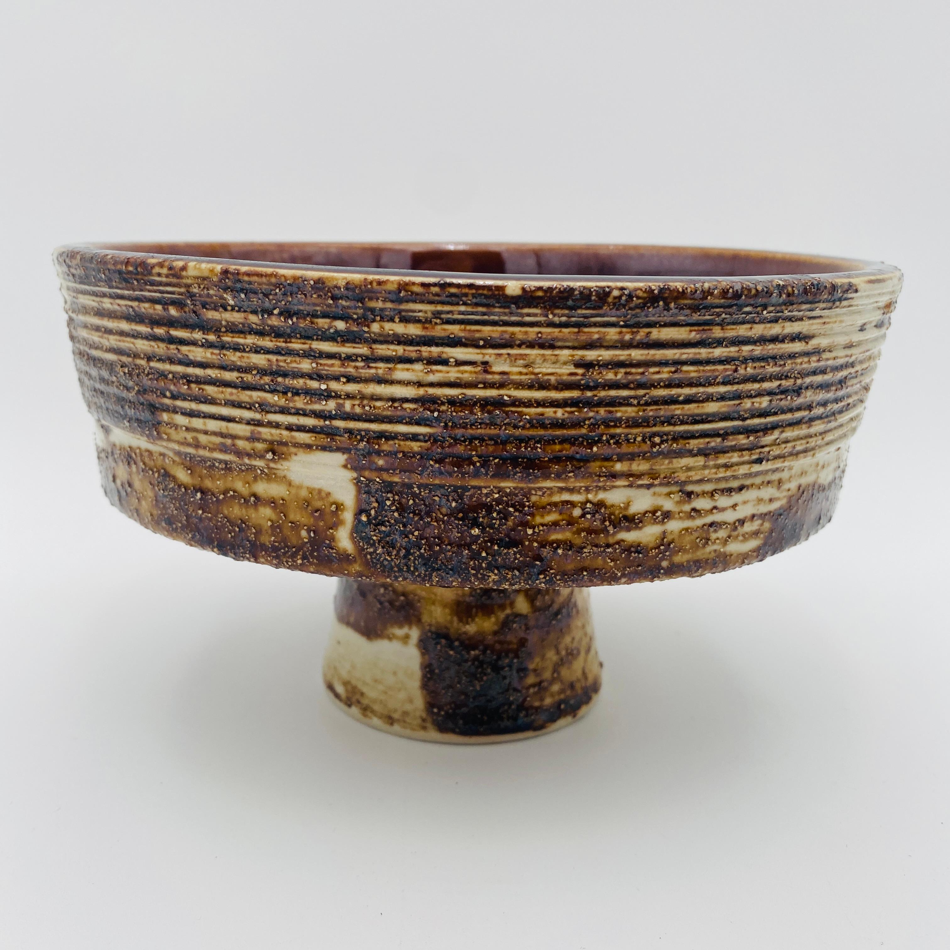 Questo vaso giapponese di Ikebana è stato realizzato negli anni '60. Ha una superficie esterna strutturata con uno smalto applicato con un pennello grande e uno smalto interno color cioccolato lucido a forte contrasto. La base con piedini crea linee