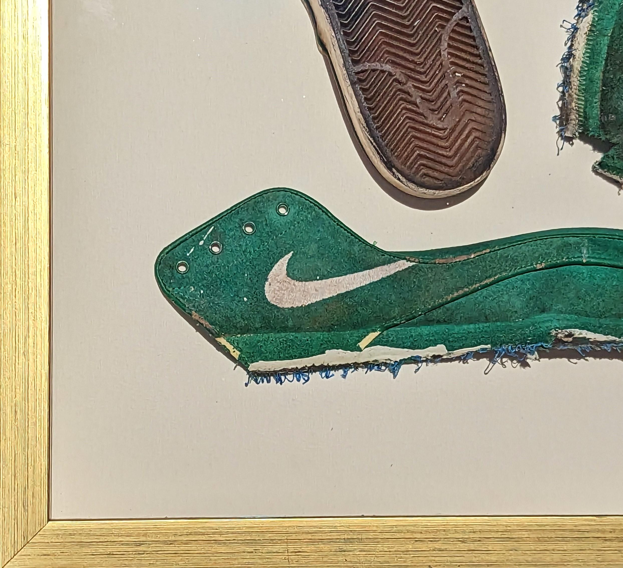 Peinture contemporaine d'objets trouvés par l'artiste Tra' Slaughter de Houston, TX. L'œuvre présente une chaussure verte déconstruite flottant dans un cadre doré. Cette pièce a fait partie de l'exposition personnelle de Tra 