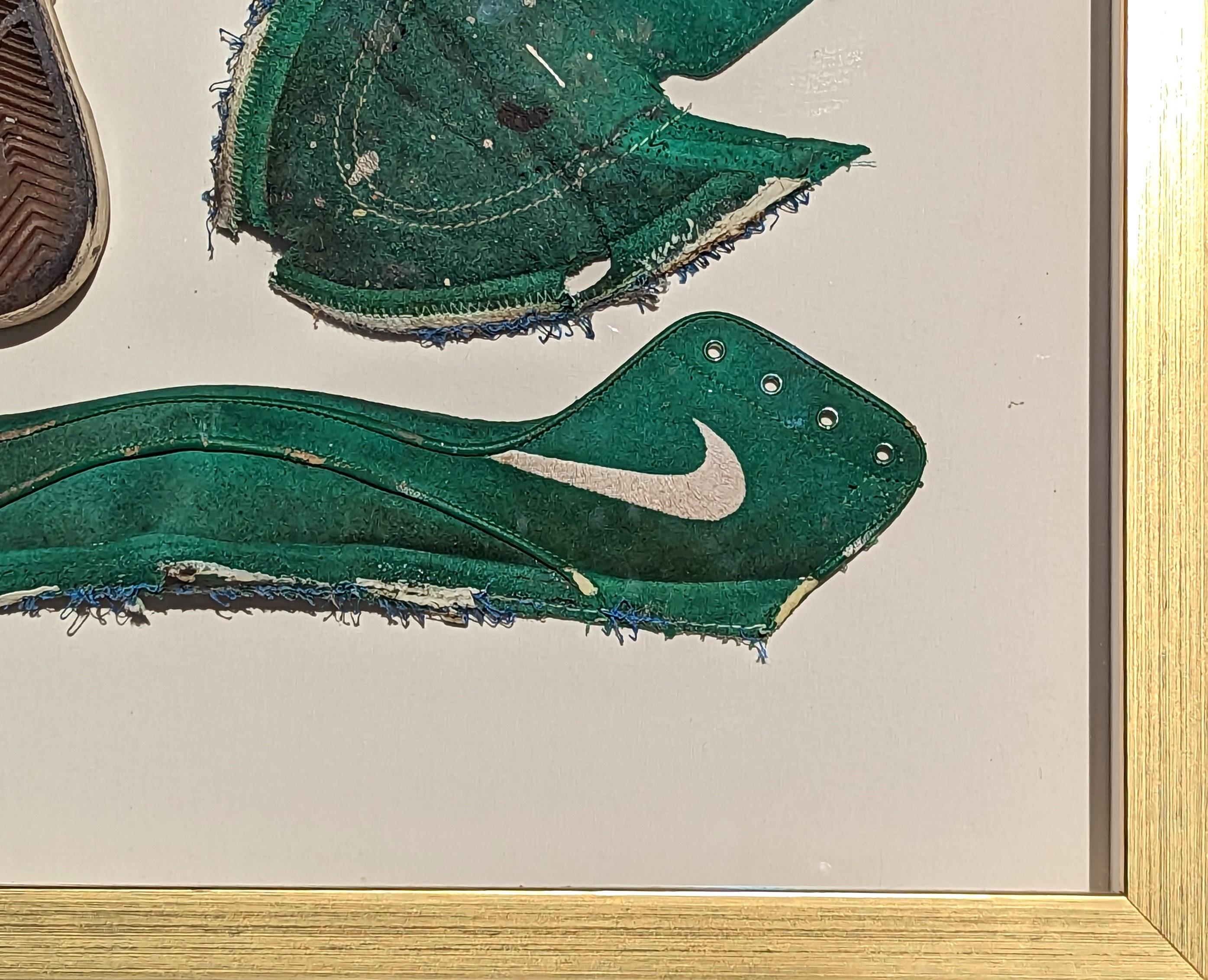 Contemporary found object painting by Houston, TX artist Tra' Slaughter. The work features a green deconstructed shoe floated in a gold frame. This piece was included in Tra's solo show 