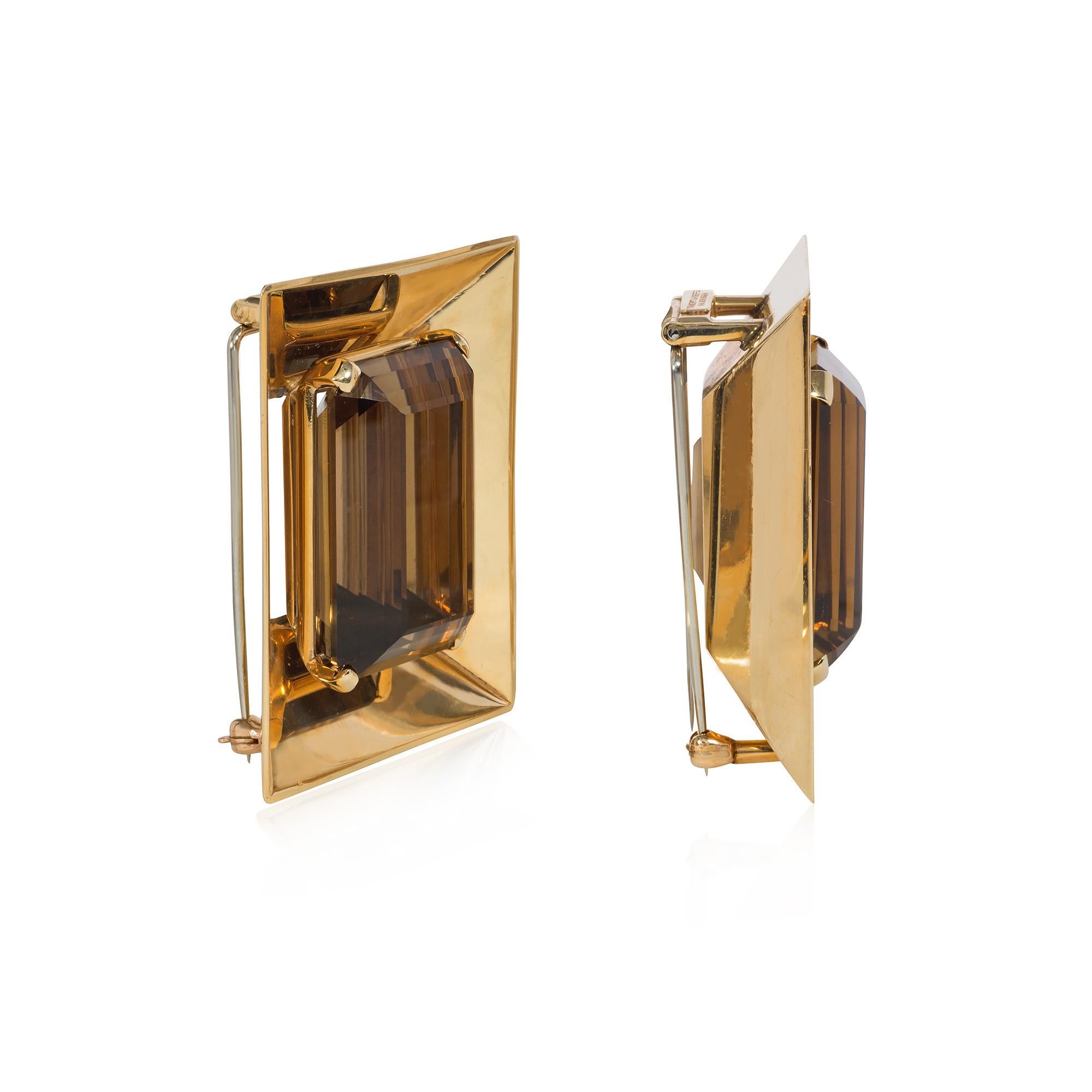 A pair of substantial Retro citrine and gold clip brooches centered by prong-set, emerald-cut citrines inside rectangular, beveled gold frames, in 14k with double pin backs. Trabert and Hoeffer - Mauboussin.  Atw citrines 55.00 cts. and 57.00 cts.,