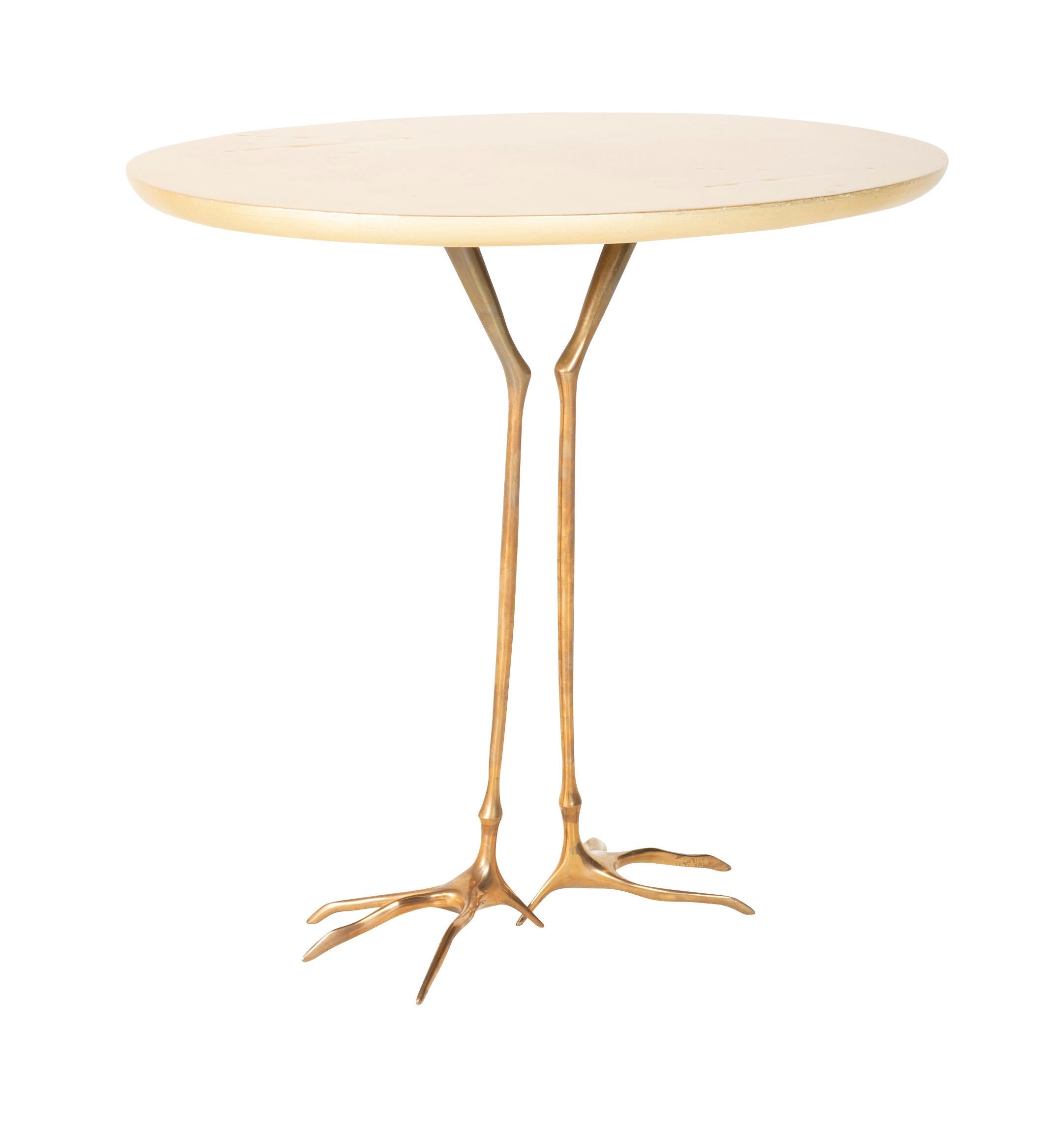 A table designed by Surrealist artist Meret Oppenheim for Simon Gavina. The 'Traccia' table has bronze bird form legs with oval gold leafed top with incised a two bird foot prints in top.