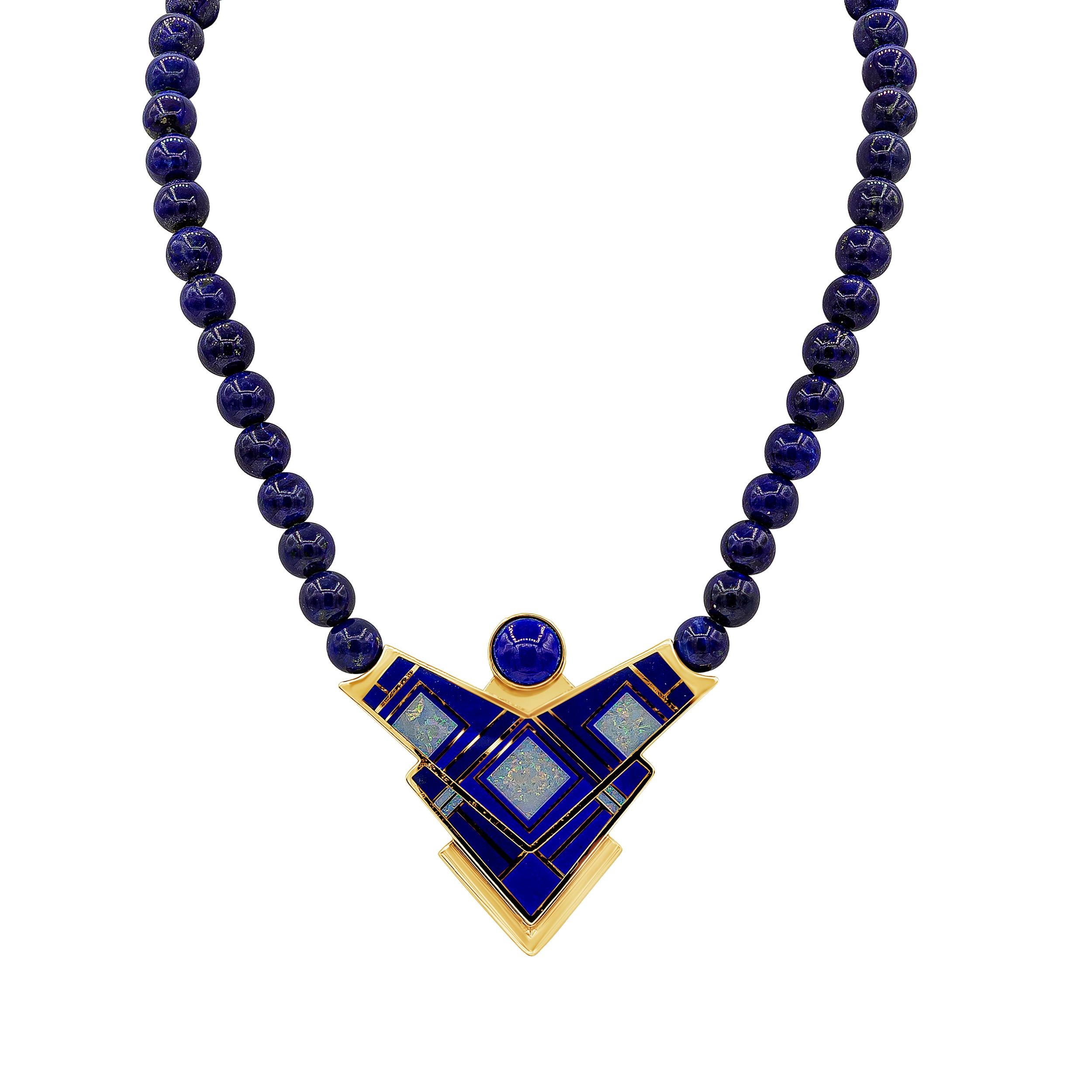 A unique necklace showcasing a geometric Native American design made of 14 karat yellow gold, accented by enamel and lapis lazuli. Pendant suspended on lapis lazuli beads. Made by Tracey Designs.

