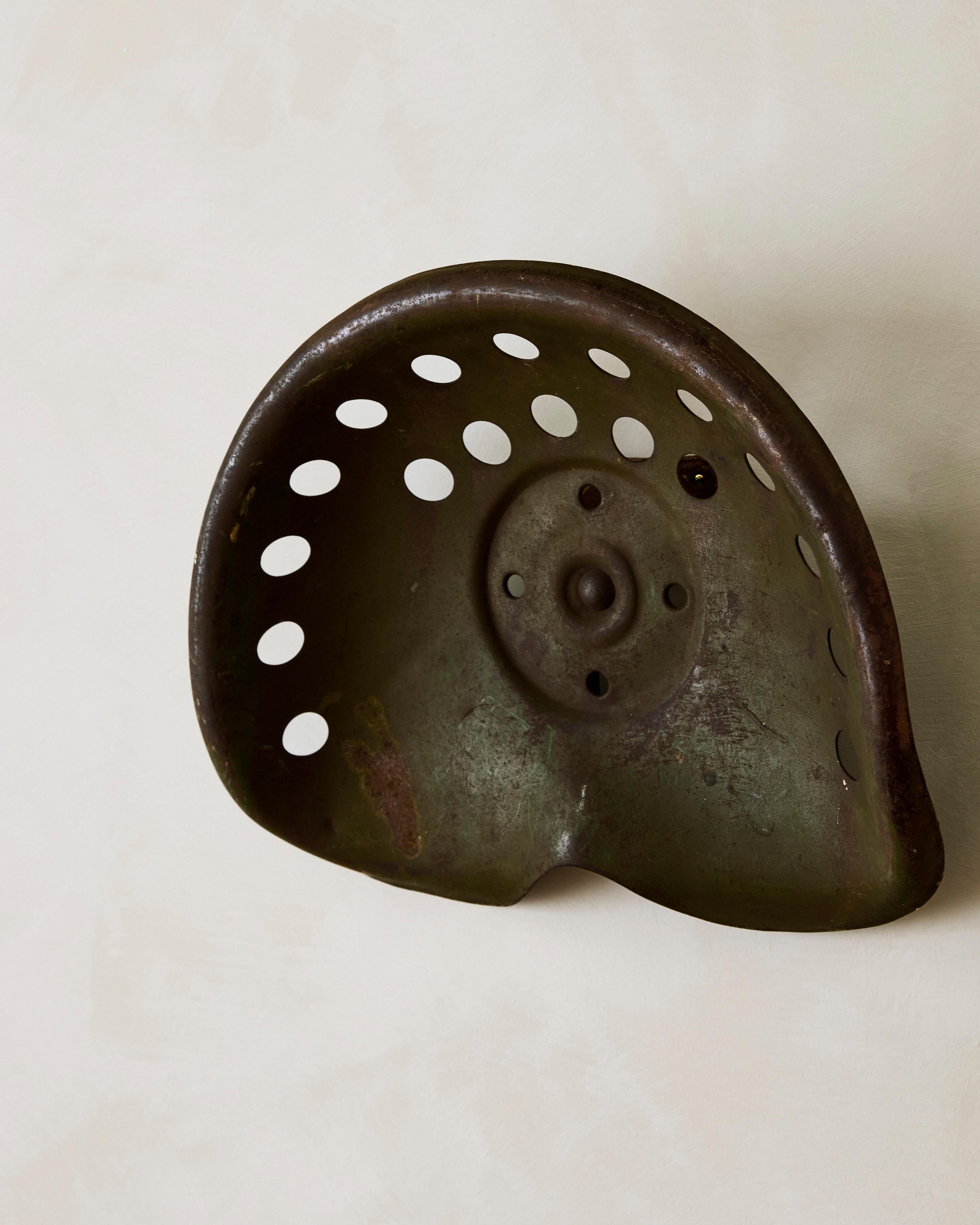 Traktorsitz-Wandskulptur aus patiniertem Metall.

