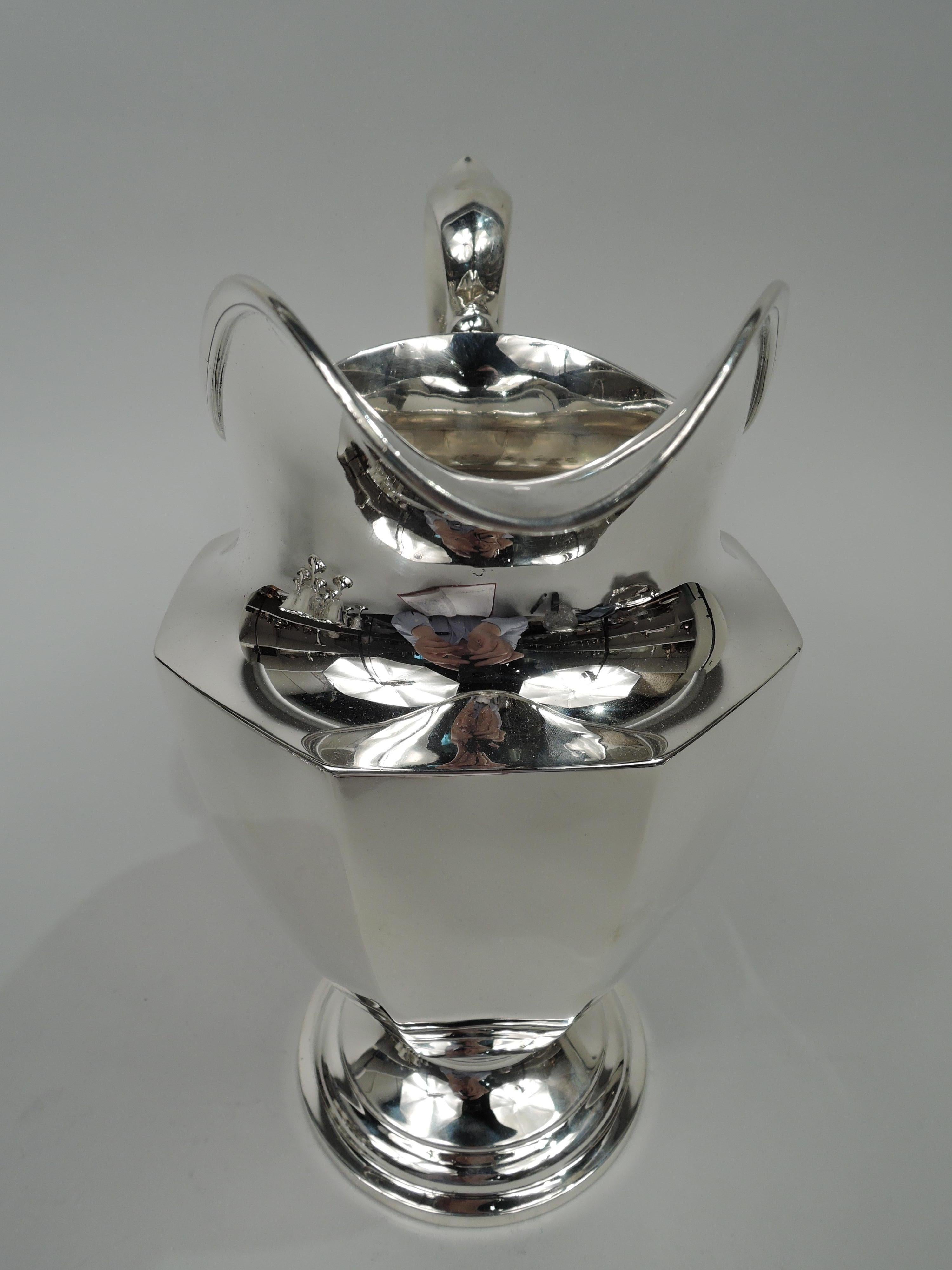 Traditional Classical sterling silver water pitcher. Made by Dominick & Haff in New York, ca 1920. Tapering and faceted bowl on round and stepped foot. High-looping capped and scrolled handle and helmet mouth. Fully marked including maker’s and