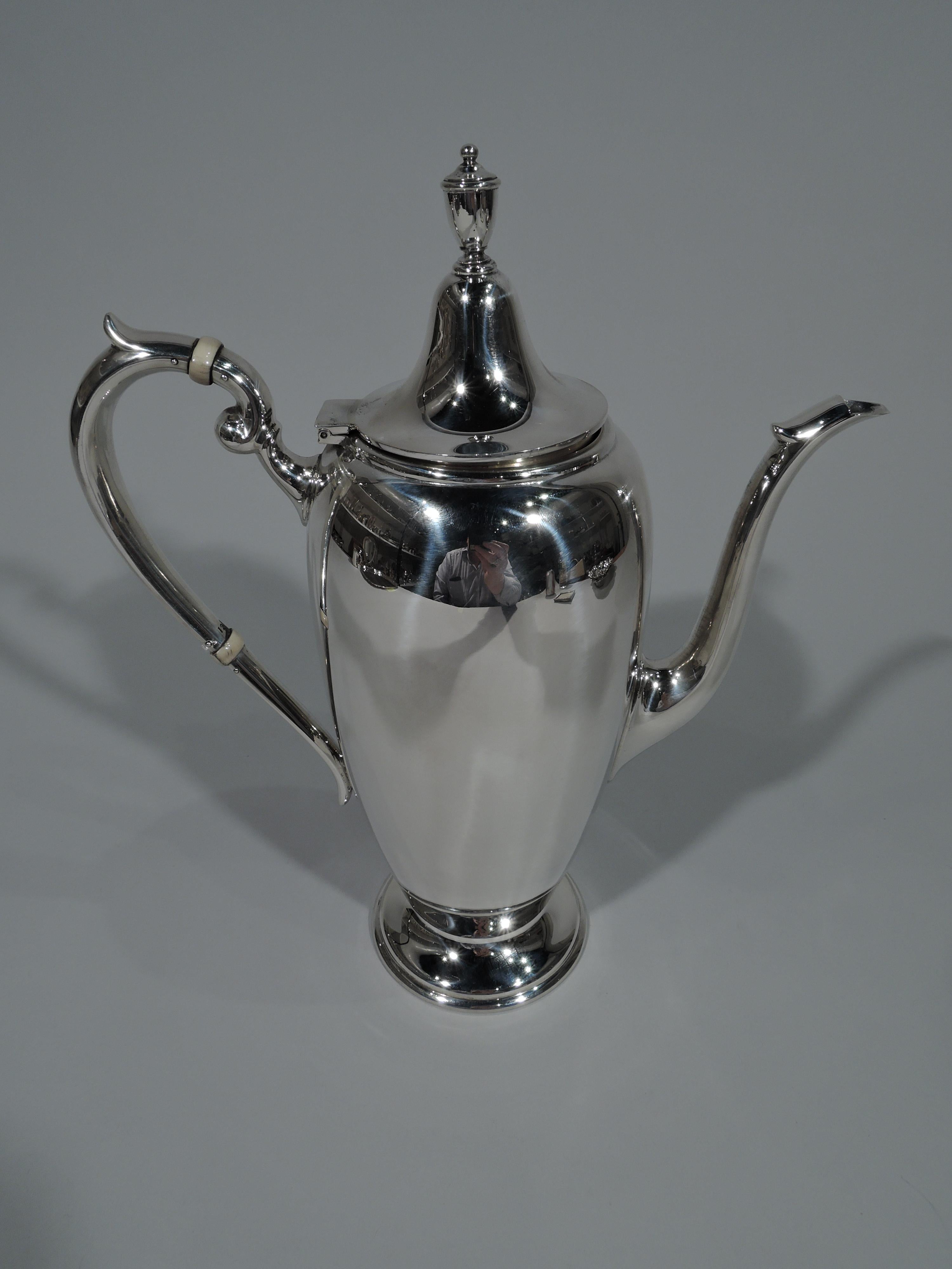 American Colonial Revival sterling silver coffeepot. Made by Gorham in Providence in 1951. Curved and tapering body, raised foot, capped high looping handle, vertical s-spout, and hinged domed cover with vase finial. A pretty piece in the