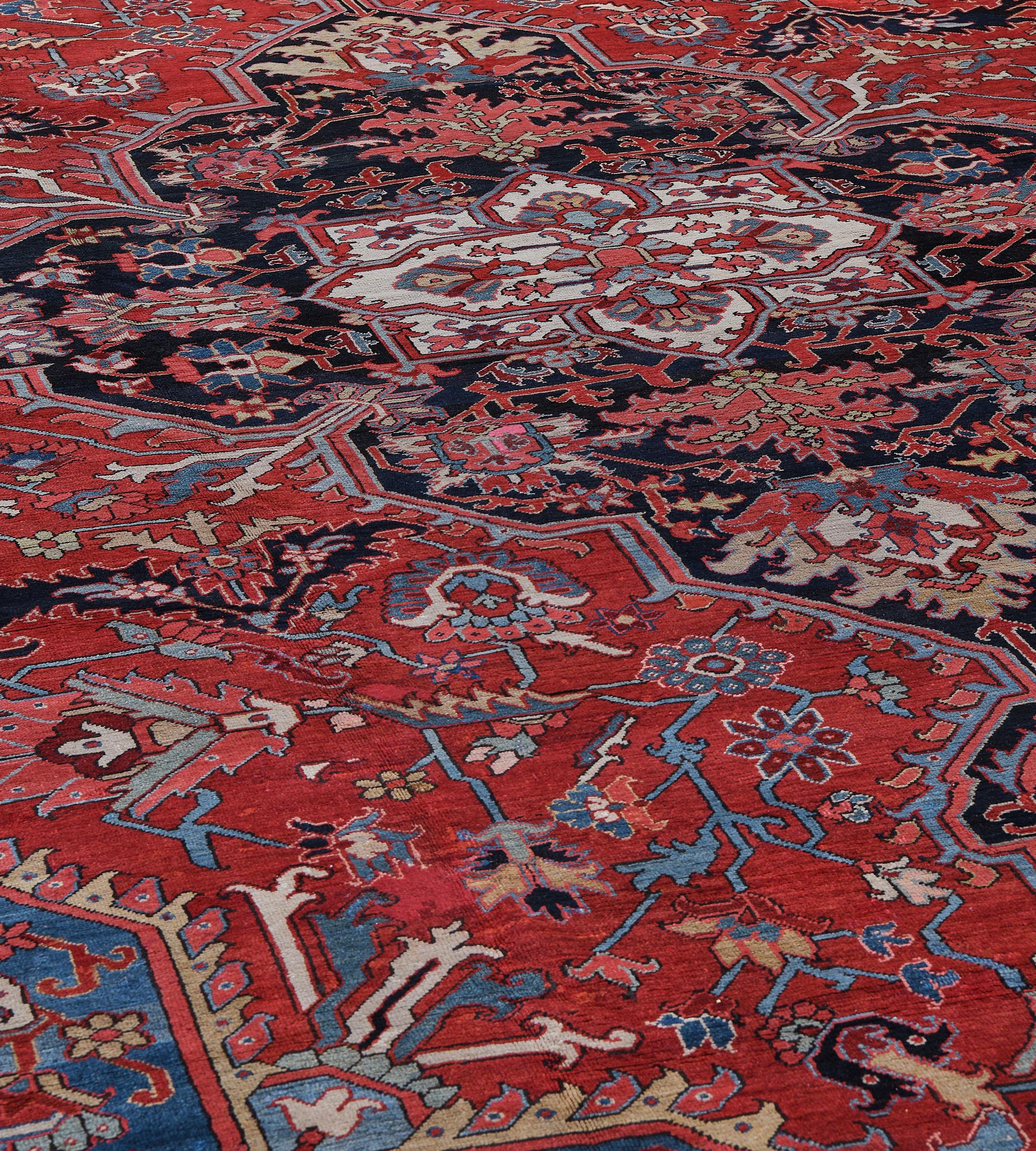 This antique, circa 1900, Persian Serapi rug has a brick-red field with palmette and serrated leaf vine around a central cusped charcoal-black medallion with similar palmette pendants containing a central ivory stepped lozenge medallion with an open