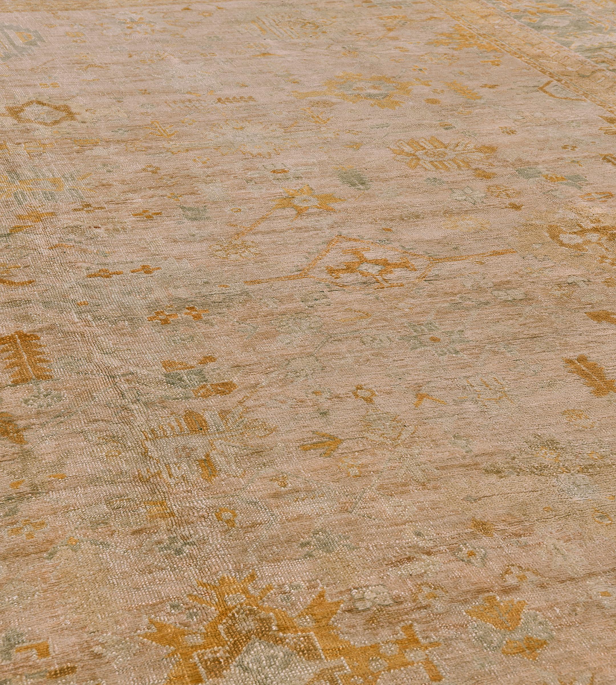 This traditional hand-woven Turkish Oushak rug has a dusty peach-rose field with a profusion of angled palmettes and floral motif vines, in a slate stylized palmette border, between complementary angled vine borders.

Antique Oushak rugs,