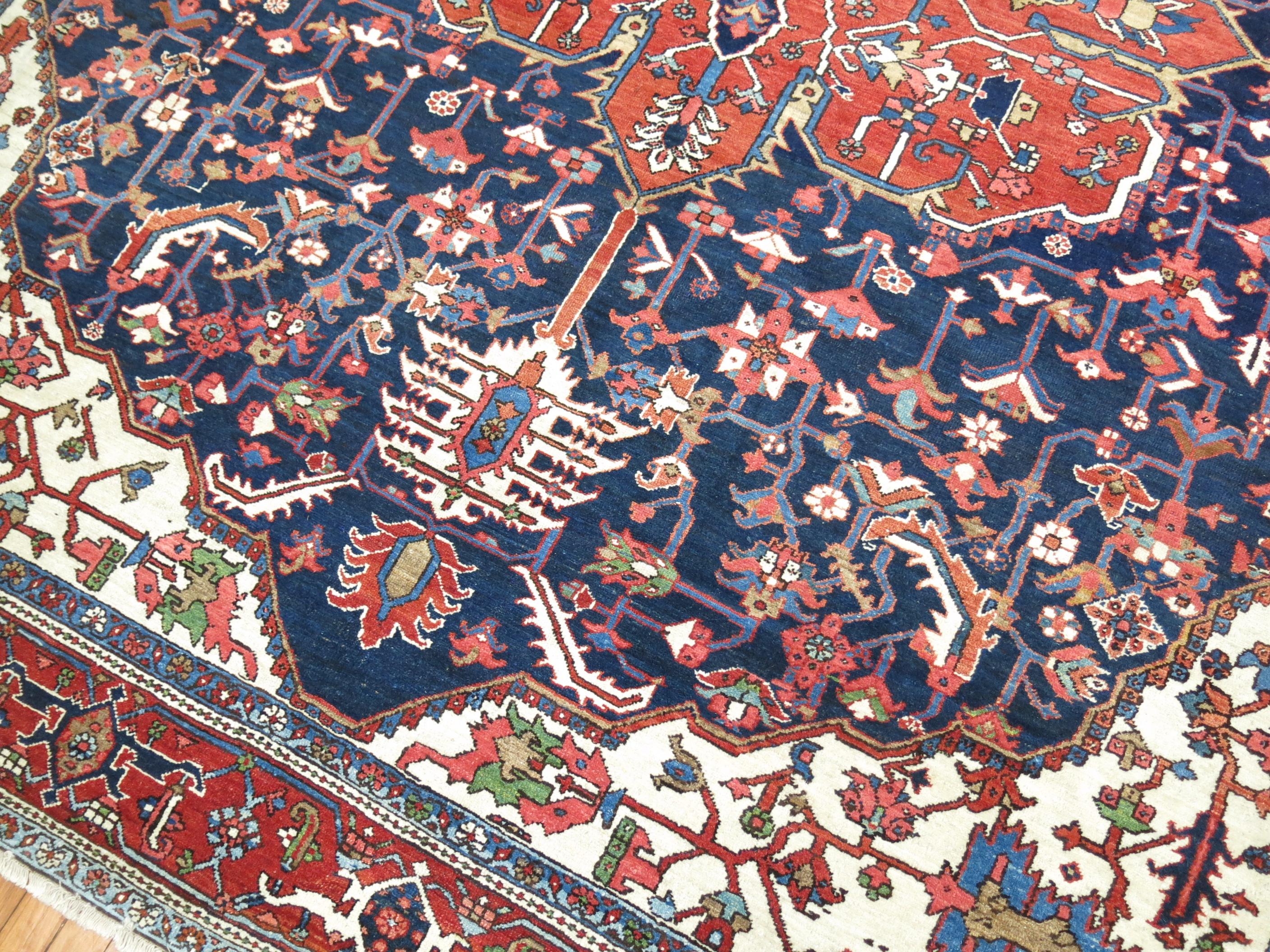 An early 20th-century traditional navy blue and brown accent, ivory field room size Persian Heriz carpet.

Measures: 9' x 11'3