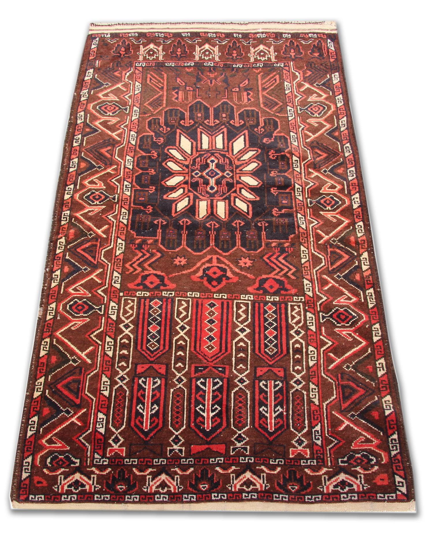 This fine wool rug was woven by hand in the 1980s in Afghanistan. The central design features a rich burgundy background with red, blue and cream accents that make up the tribal design. Intricately woven with delicate detail through both the centre