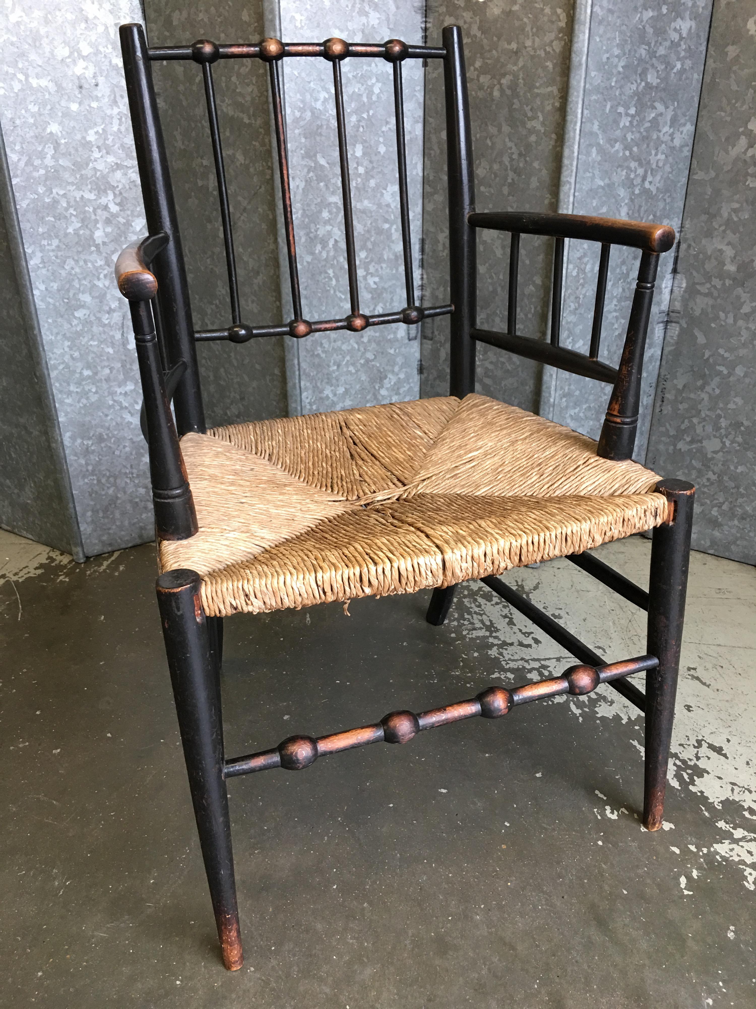 Original Sussex armchair in ebonized beech with rush seat. These were found and copied by William Morris, liberty’s and heals and were sold by them. This chair has patina consistent with age and use.