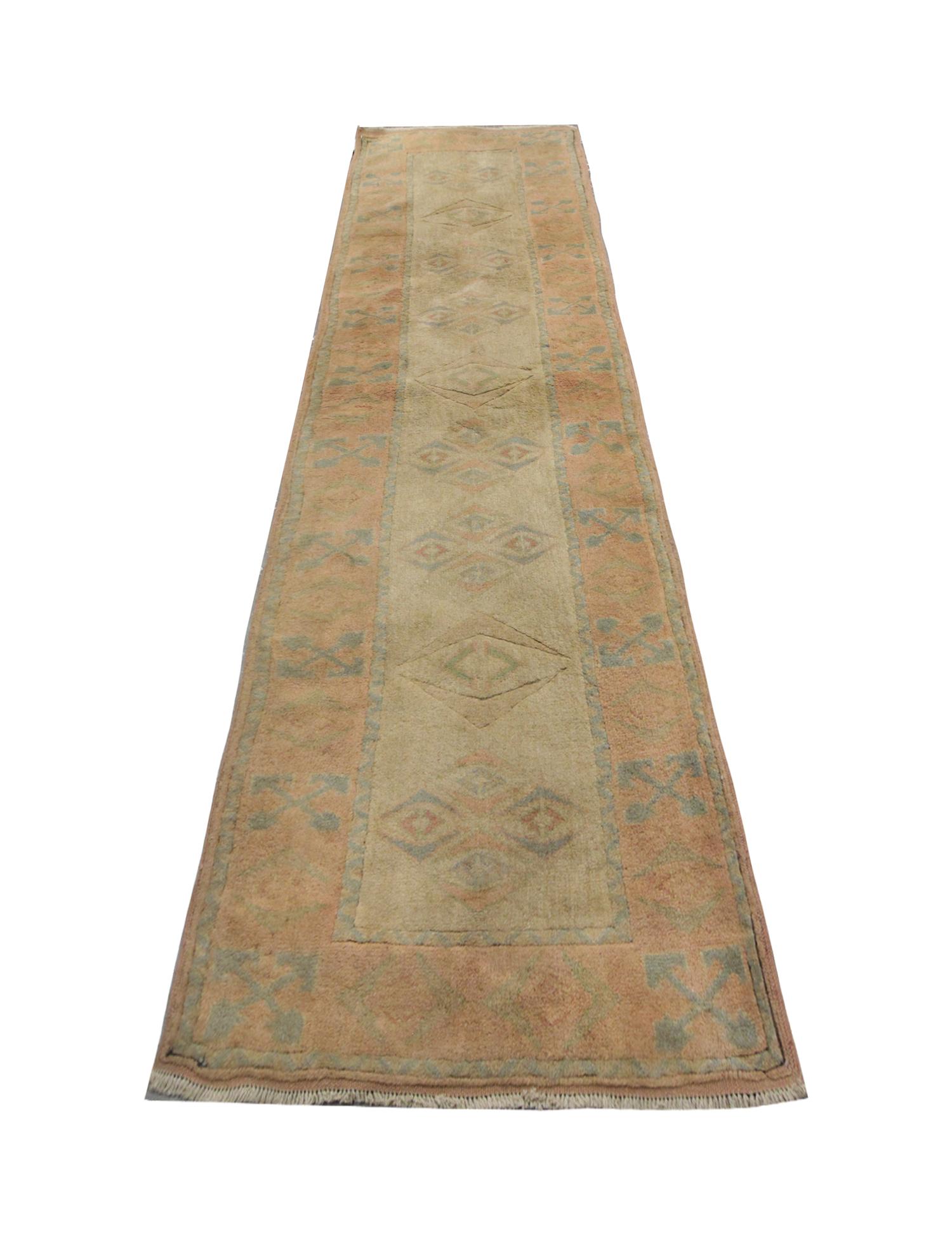 Subtle muted colors have been used in the construction of this high-quality, long antique runner. Cream and peach tones have been used as background colors for this Oriental rug, decorated with simple repeat geometric patterns. This traditional