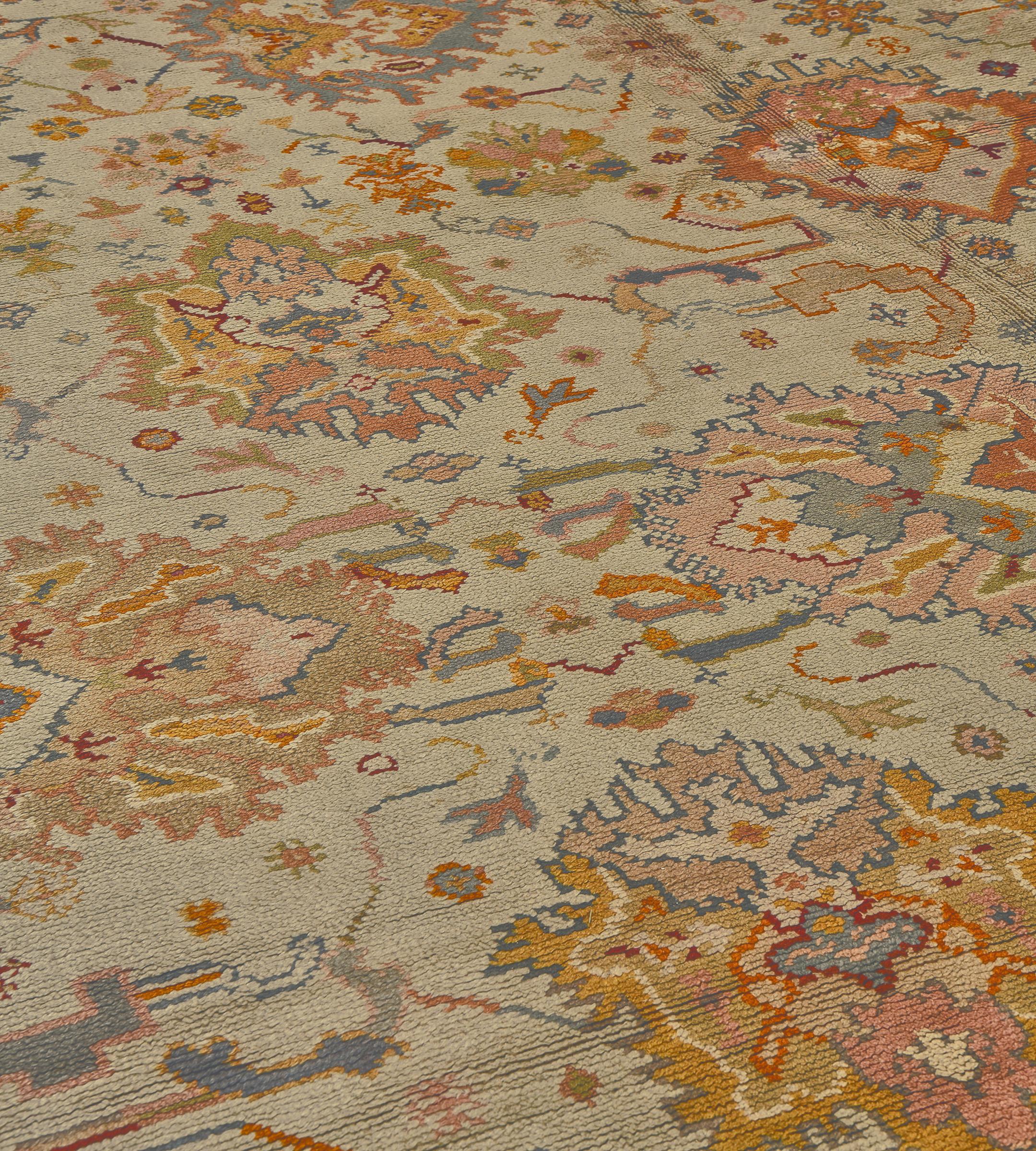 This traditional hand-woven Irish Donegal rug has a saffron-cream overall field with broad polychrome palmettes issuing delicate angled floral vines, in a slate palmette border, between geometric and floral elegant sub-borders.