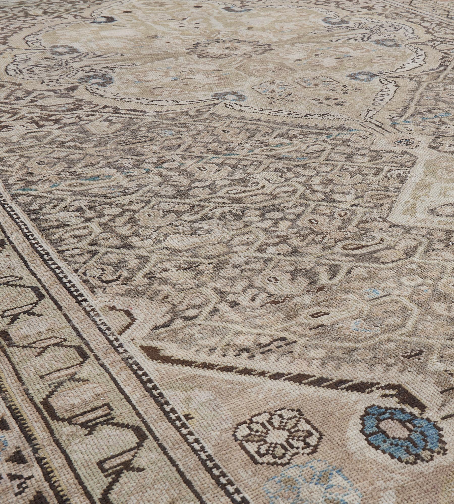 This antique Malayer rug has a shaded grey-blue field with an overall ivory angular boteh vine around a large ivory and pistachio-green cusped medallion with shield palmettes, the shaded grey-brown spandrels with stylized vases issuing a variety of