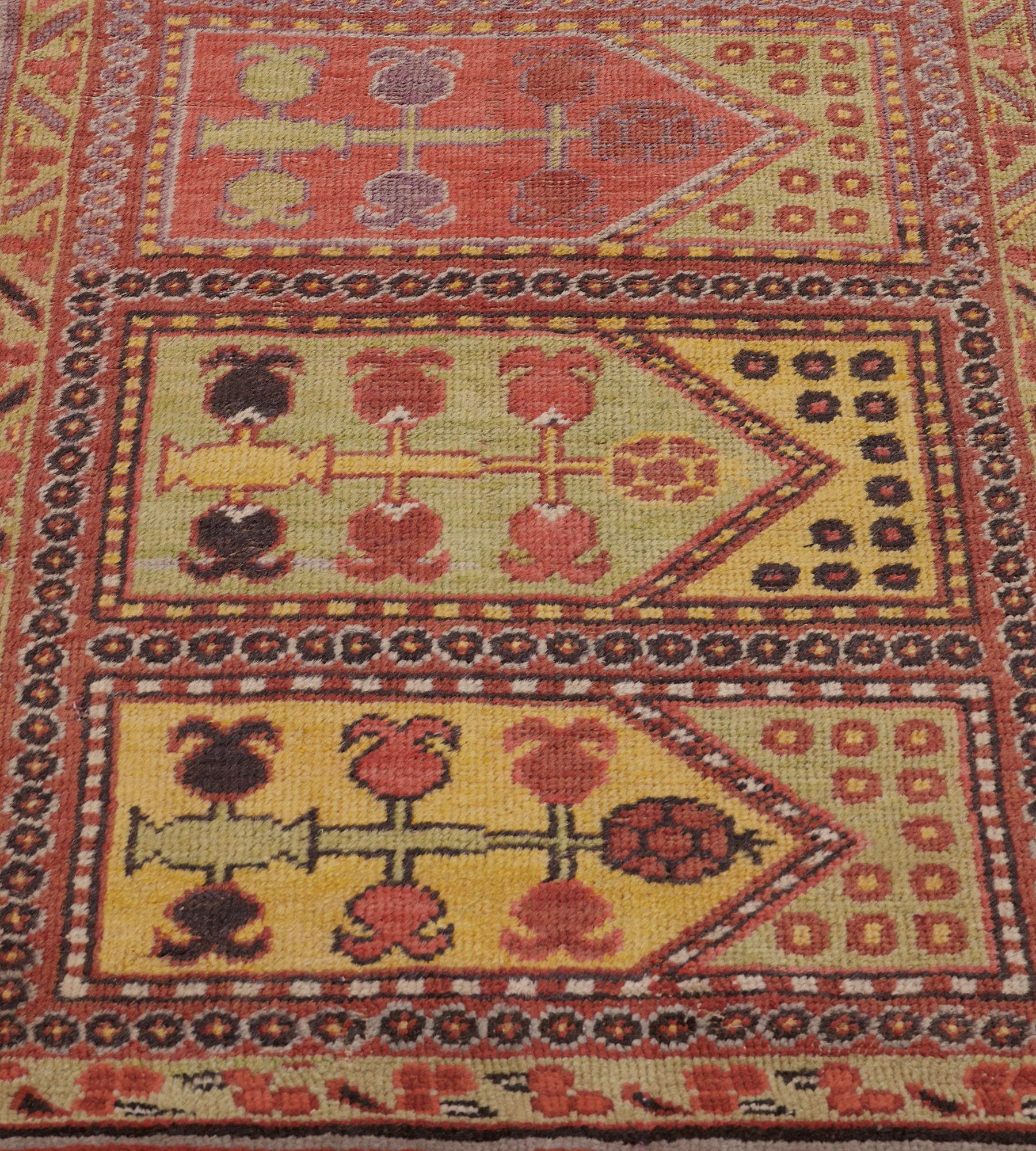 This antique, circa 1890, Khotan runner has a field with eight horizontal polychrome panels each with a vase issuing an angular pomegranate vine, the polychrome arched panel above with stylized flowerheads, in a brick-red surrounding minor stripe