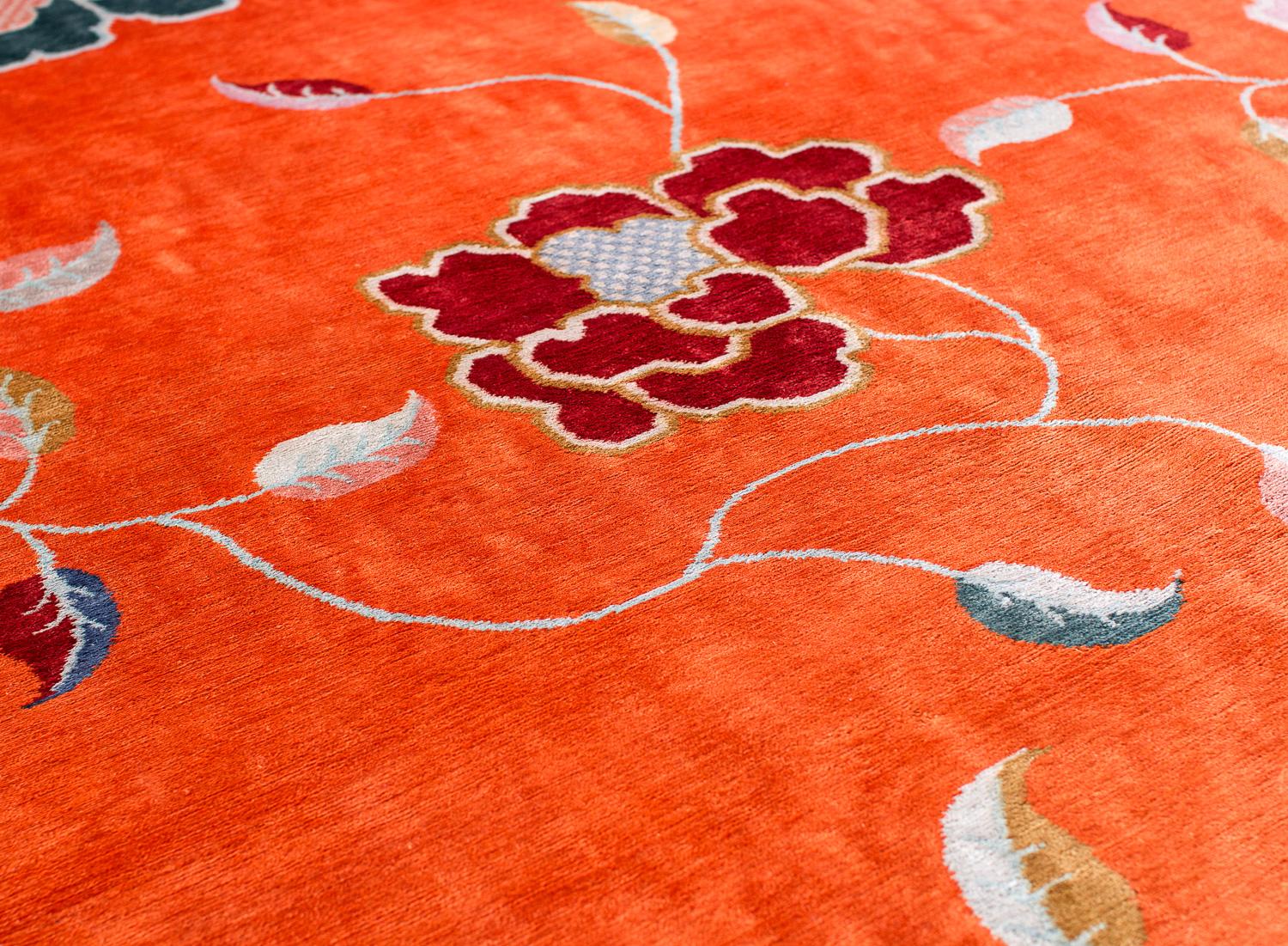This 10' (W) x 14' (L) area rug exudes sheen with the highest quality silk. The design, Kapsu Pesar bridges the old with the new. A traditional teal and pink floral design ornaments the center over a bright orange field. This Joseph Carini original