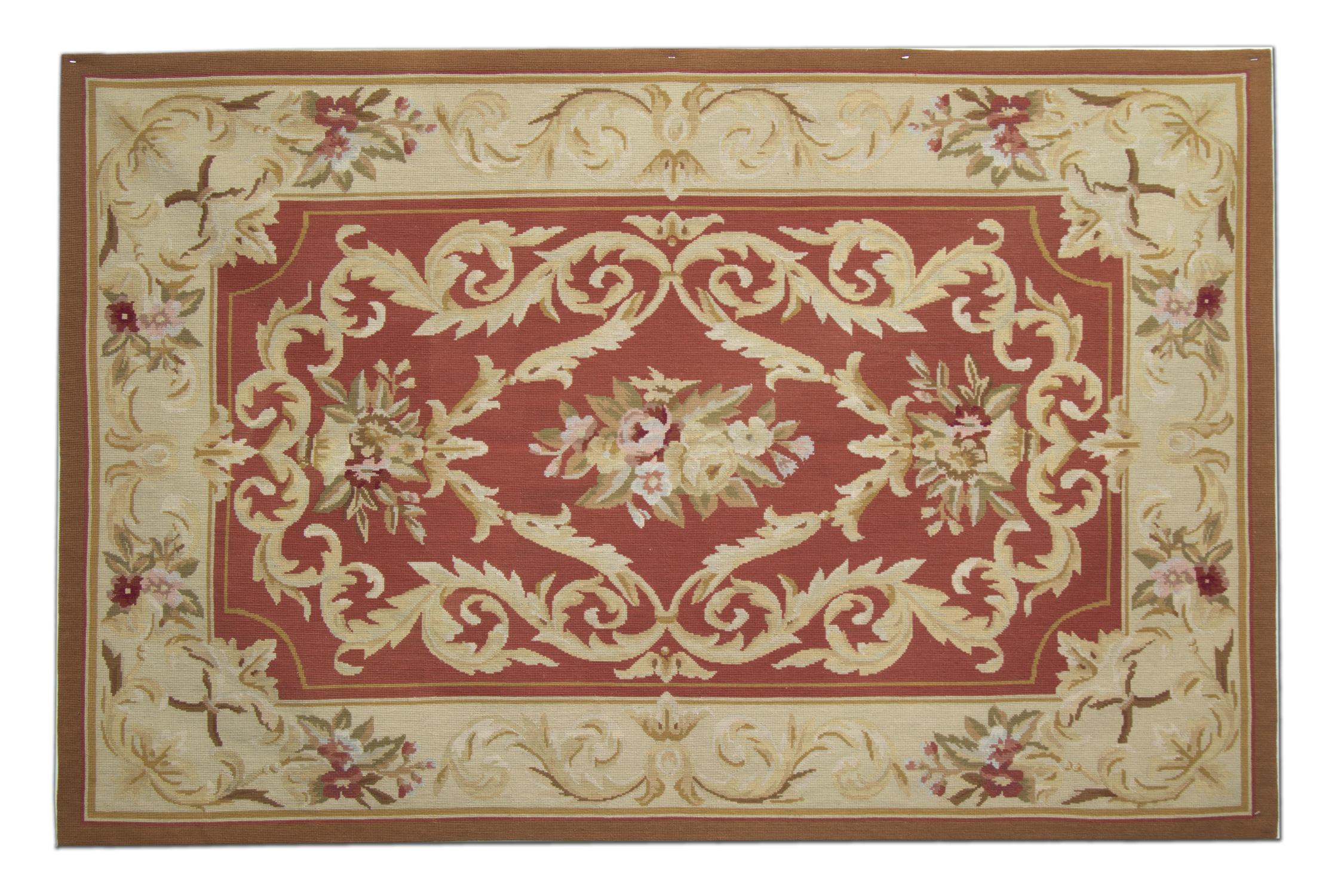 Cette tapisserie à l'aiguille simple mais élégante a été tissée à la main dans des couleurs rouge et beige. Le motif central a été tissé sur un fond rouge rouille et présente un médaillon floral symétrique. Le tout est ensuite encadré par une