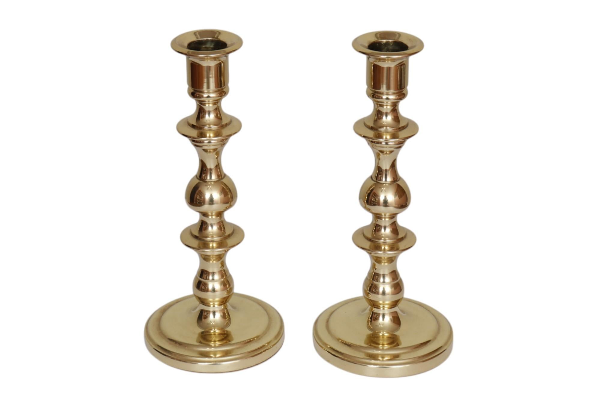 Ein Paar Kerzenhalter aus Messing im traditionellen Stil, hergestellt in den Vereinigten Staaten von Baldwin. Schlanke gedrehte Säulen mit glatten Wachsschalen haben eine sanfte Balusterform mit zwei Knäufen. Runde, flache Sockel haben eine