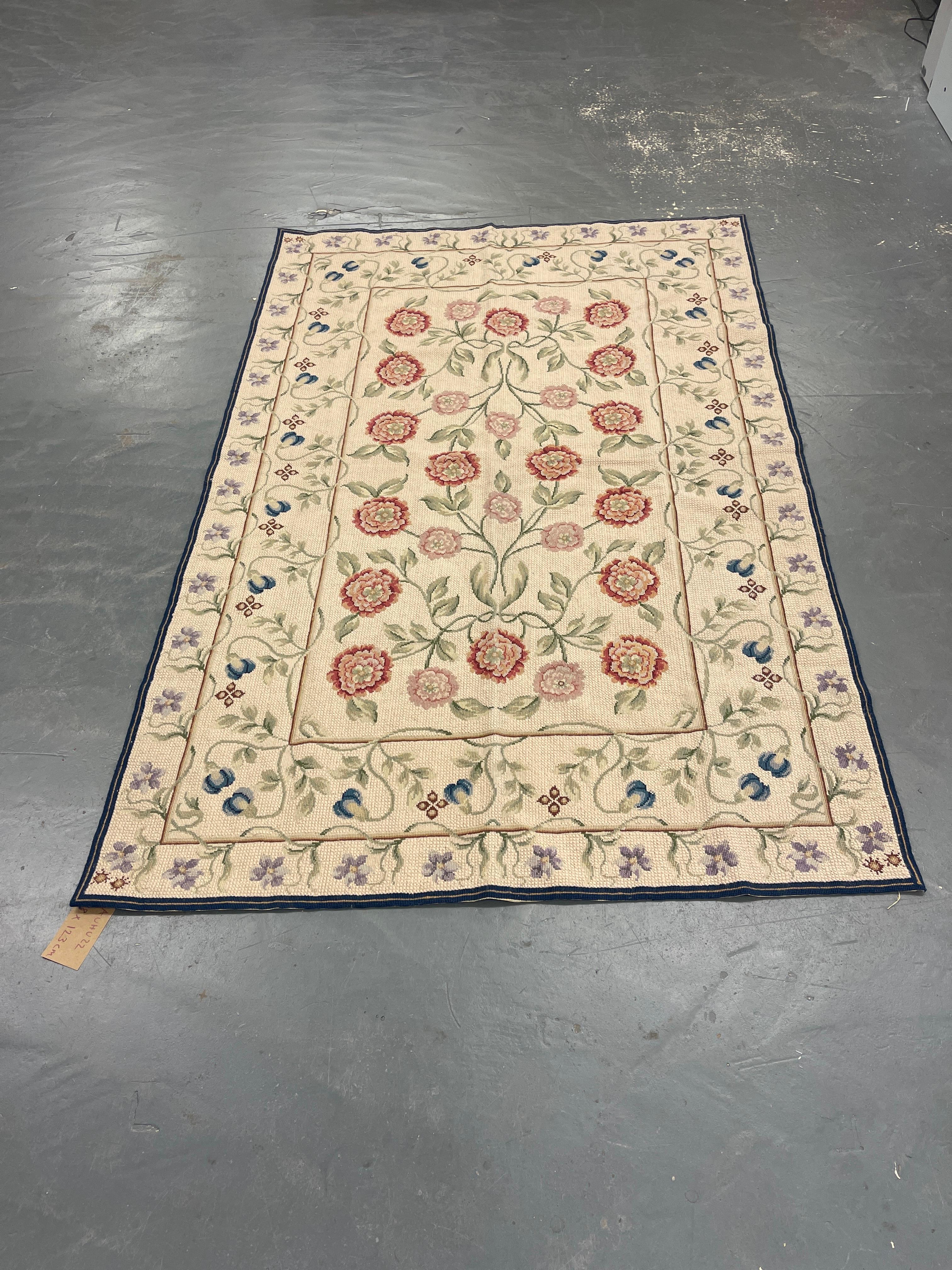 This fantastic area needlepoint rug has been handwoven with a beautiful all-over bunch of floral designs woven on a cream ivory background with cream green and ivory accents. This elegant piece's colour and design make it the perfect accent