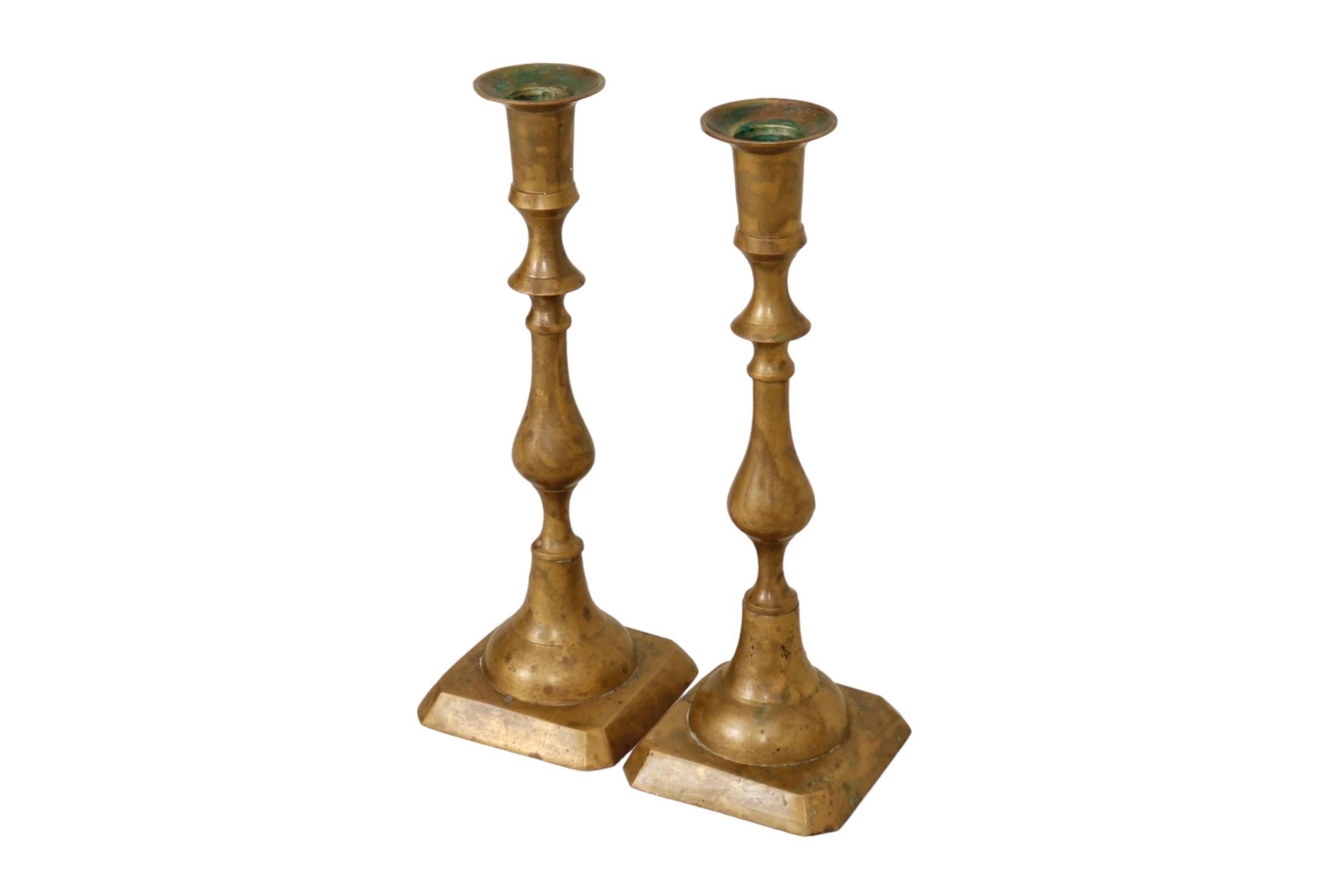 Paire de bougeoirs traditionnels en laiton. Les colonnes balustres simplement tournées sont surmontées d'appliques élégantes et terminées par des bases carrées. Légère patine d'usage. Dimensions par bougeoir.
