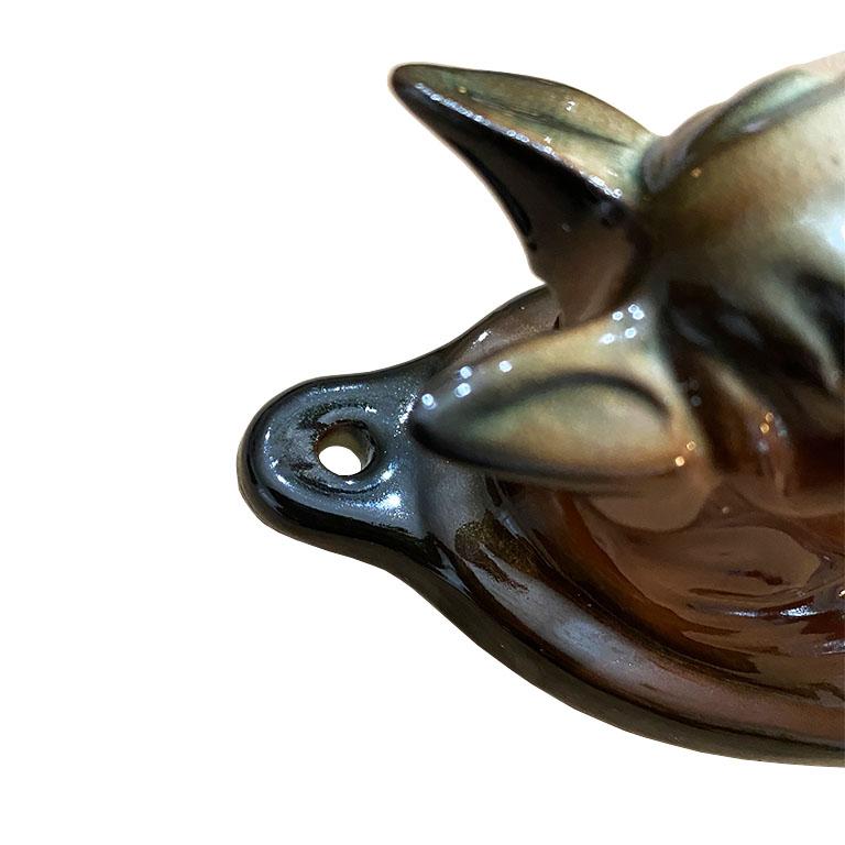 A traditional equestrian style ceramic wall vase in brown. This unique vase is meant to be hung on a wall or other flat surface. The vessel is in the shape of a horse head, and is painted and glazed in brown, white and black. The back is glazed in a