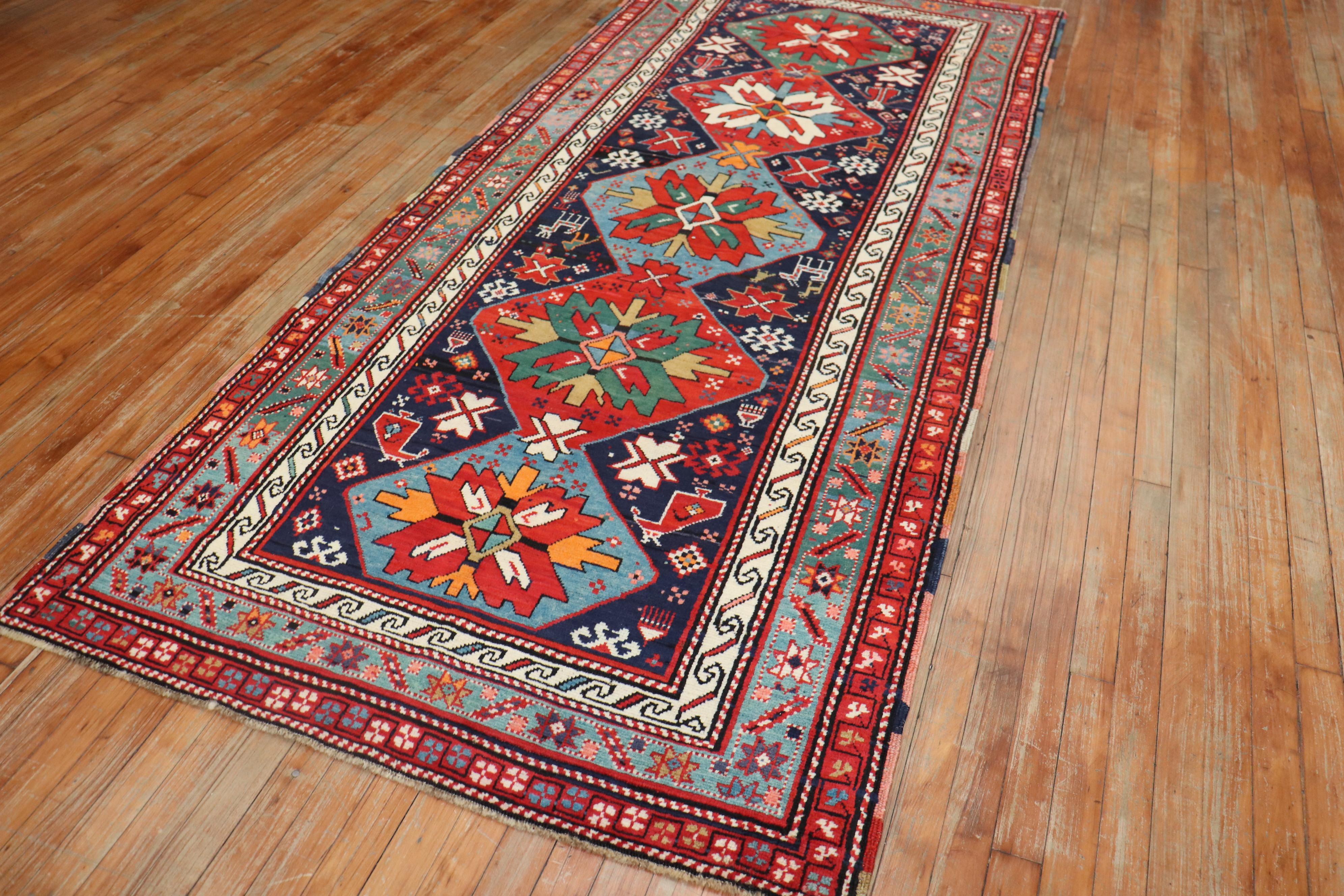 An early 20th century Caucasian Karabagh runner featuring a traditional motif in lively colors. The field is navy, green and tomato red accents. Some human figures can be spotted on the field

Measures: 3'11
