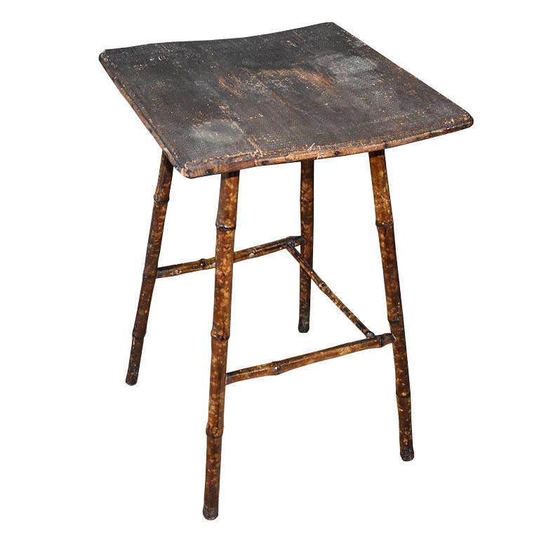 A very old, antique burnt bamboo side table. This side table or accent table is made of a combination of wood and burnt bamboo. The top is square and covered in cane or rush. It has four splayed bamboo legs, each with a stretcher connection one to