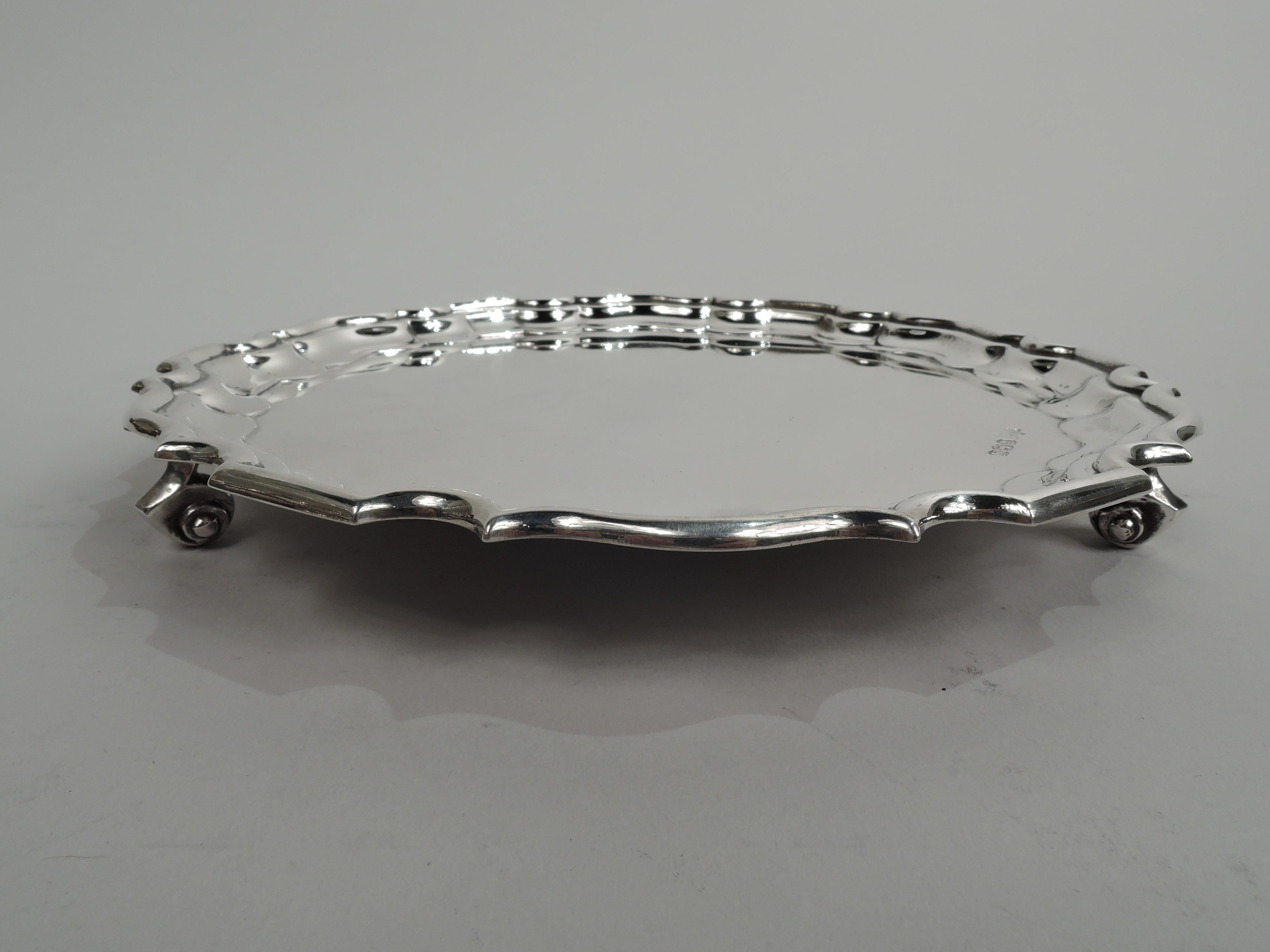 George VI sterling silver salver. Made by Walker & Hall in Sheffield in 1940. Round well with traditional molded curvilinear piecrust rim. Three volute-scroll supports. Fully marked. Weight: 11 troy ounces. 