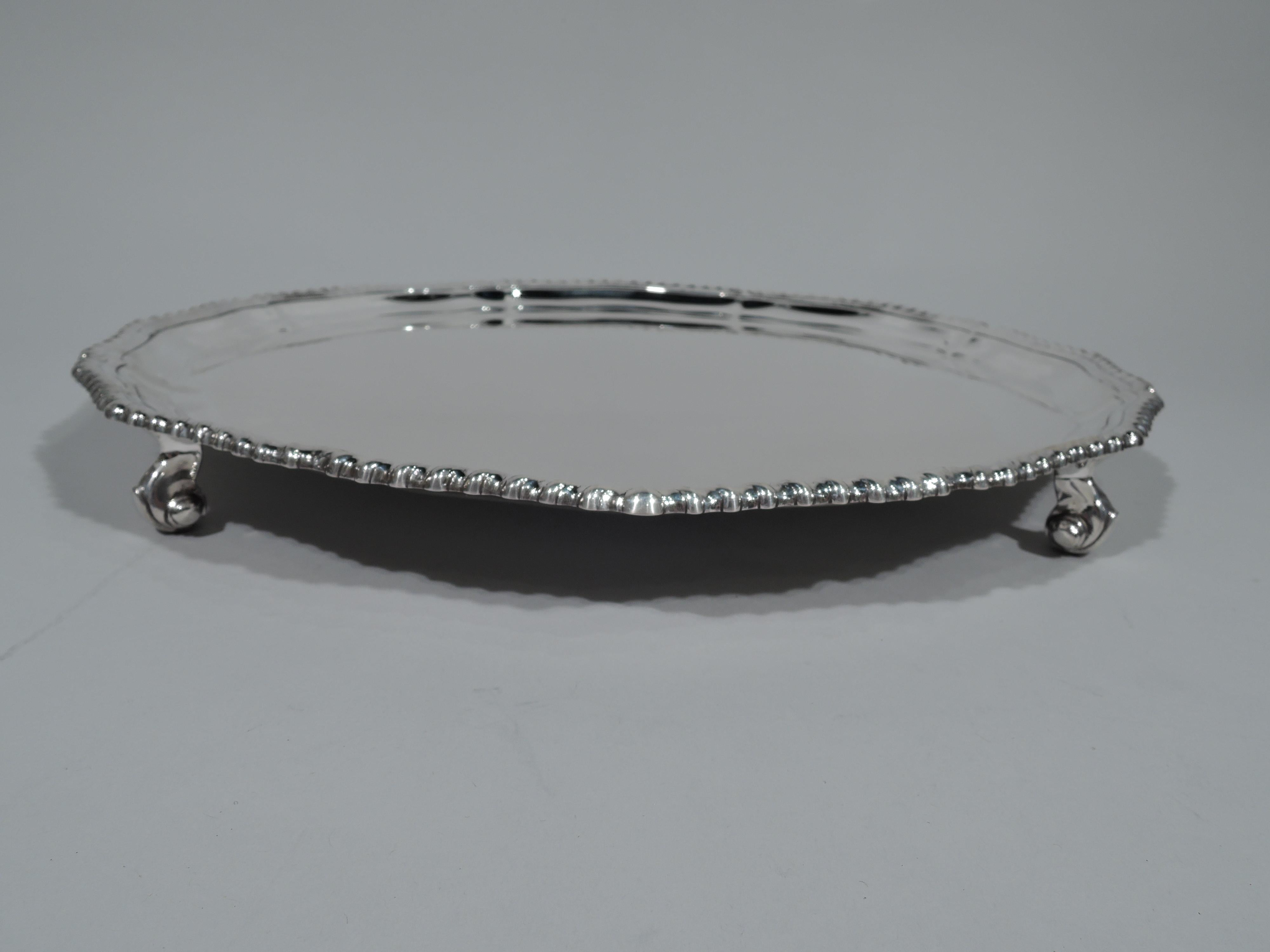 Traditional Georgian sterling silver salver. Made by Roberts & Belk in Sheffield in 1974. Round with undulating scrolled and gadrooned rim. Rests on 4 capped volute scrolls. Fully marked. Weight: 29 troy ounces.
