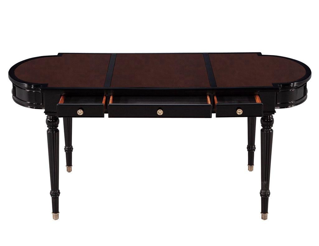 Traditional English leather top black lacquered writing desk. Newly made in the USA with iconic English traditional styling. Featuring imported Italian burgundy leather top with a polished black lacquer finish. Completed with brass hardware and